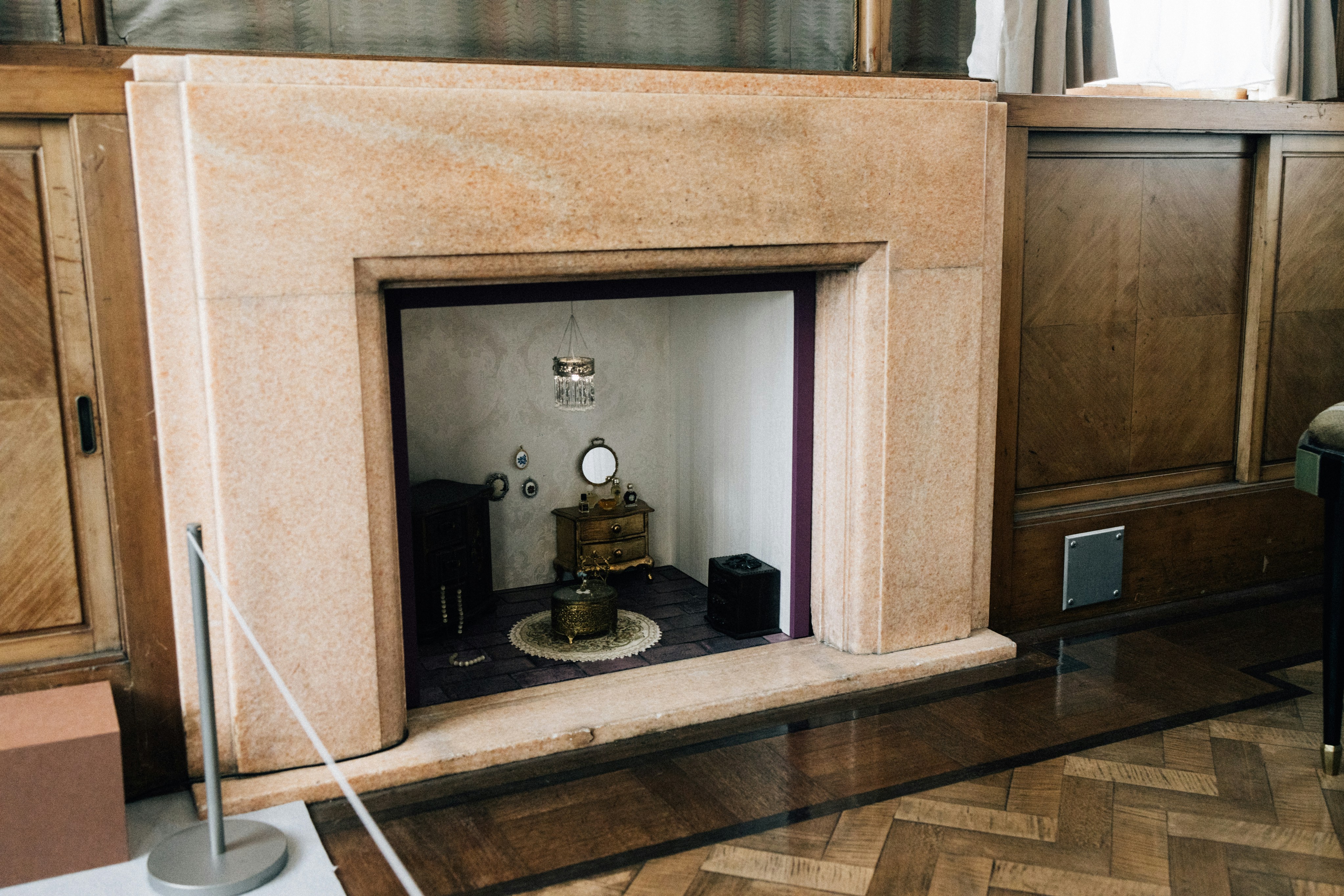 A marble fireplace with a miniature room inside.
