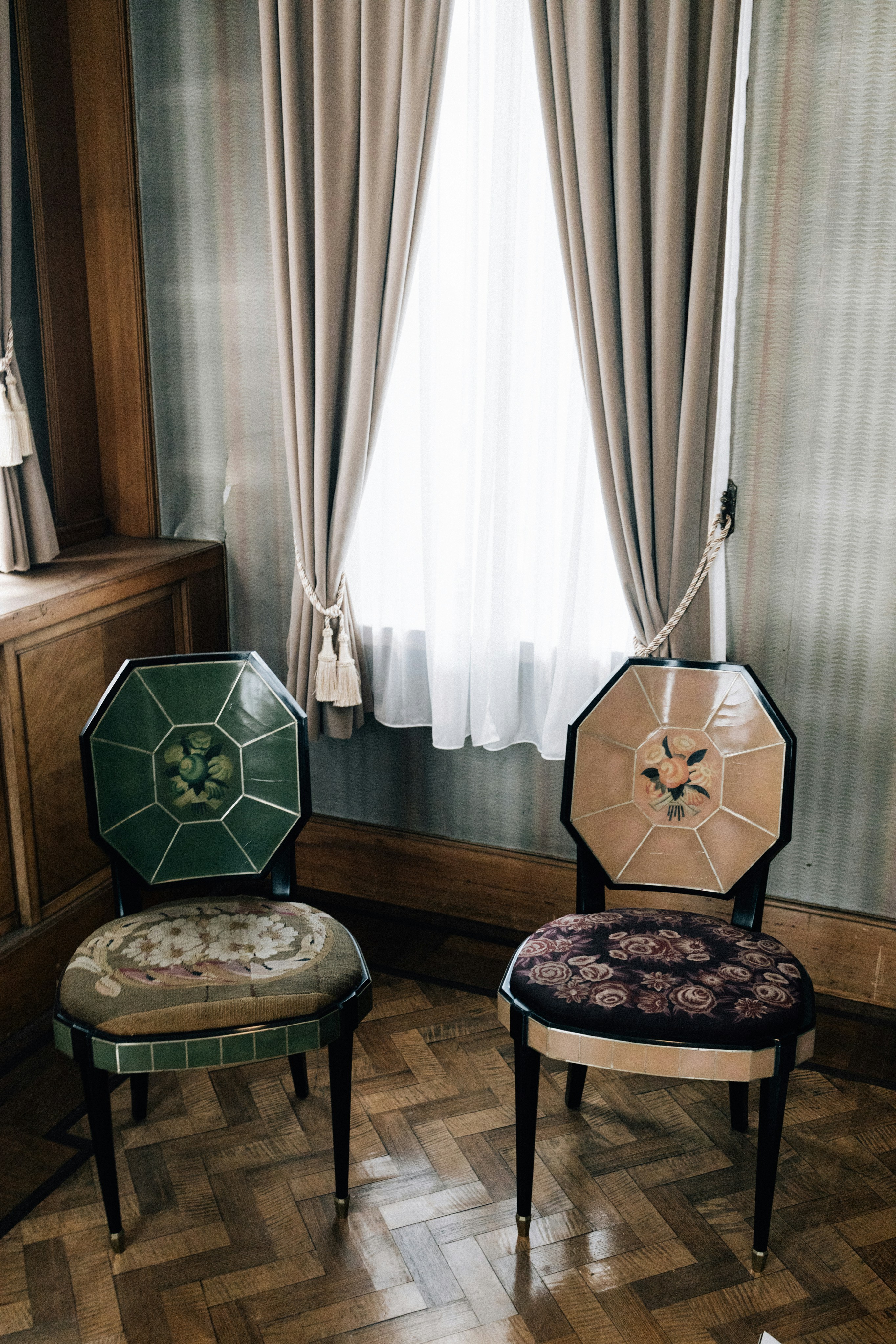 Two ornate chairs in front of a window