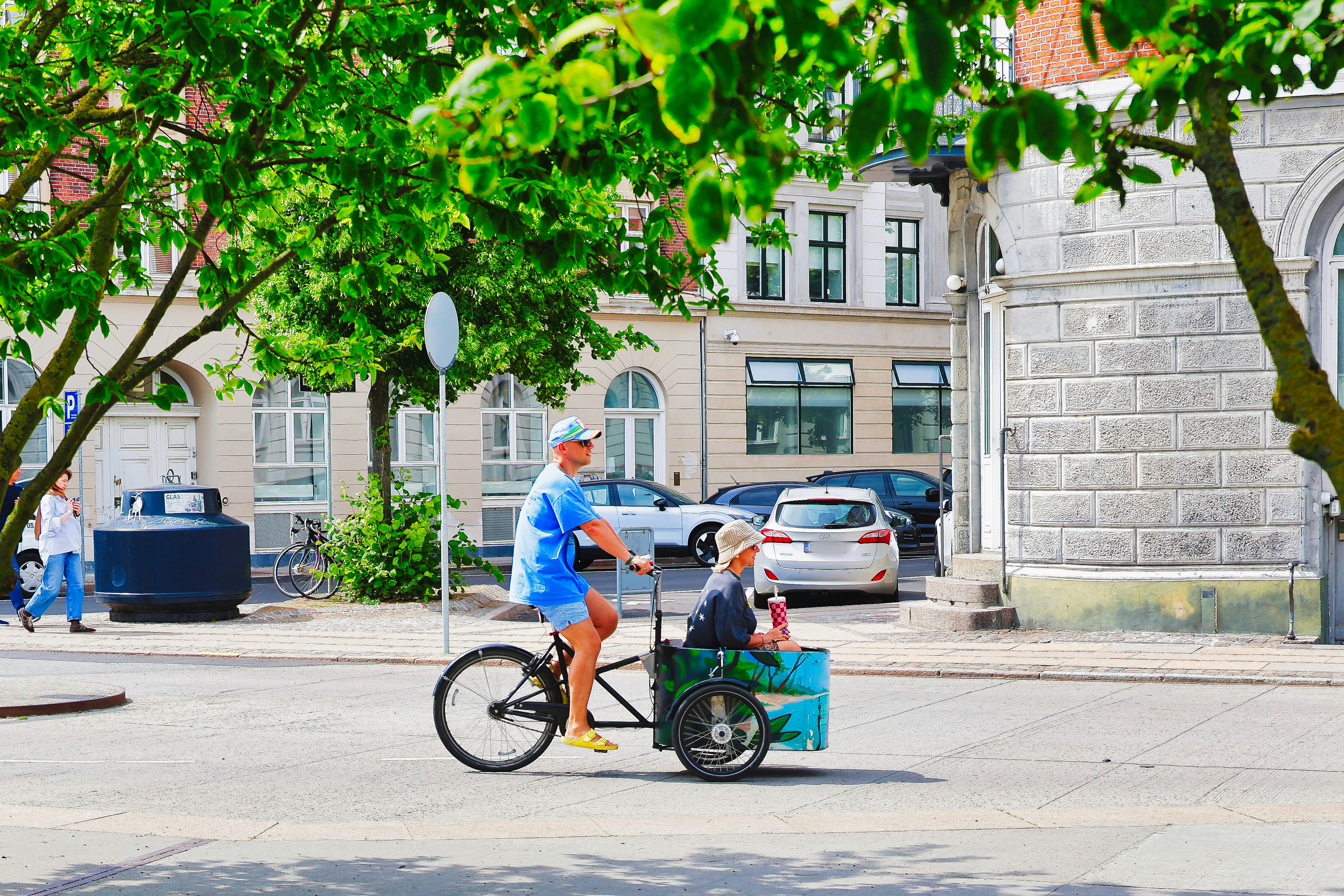 Man rides bicycle with child in cargo box.