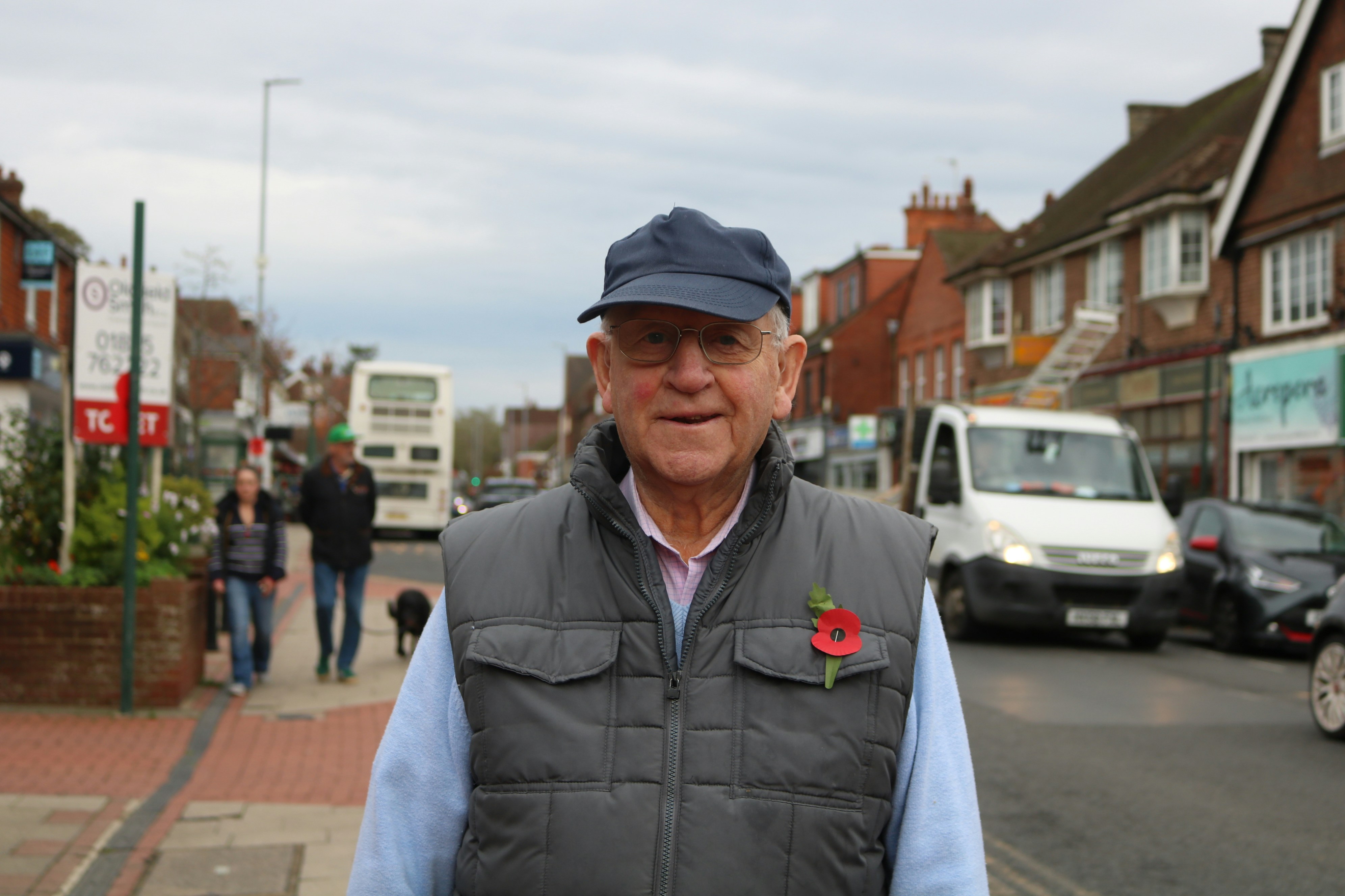 An elderly man wearing a poppy on his vest.