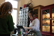 A cashier serves a customer at a shop counter.