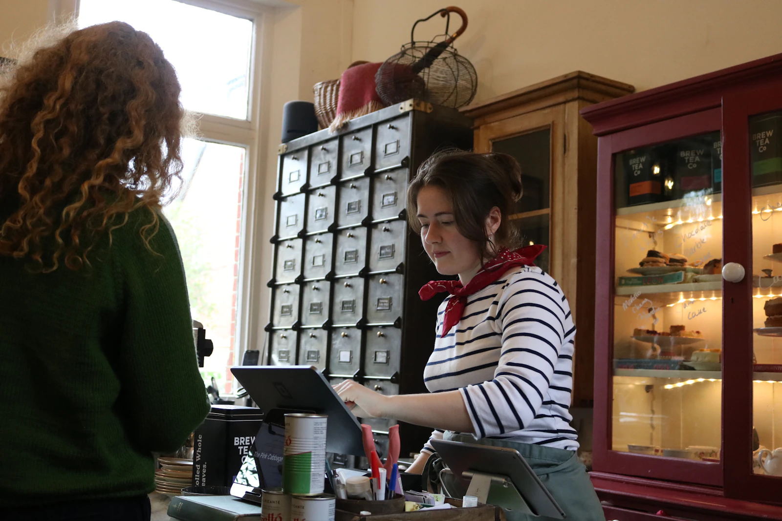 A staff member serving a customer at a shop counter, the daily transaction cannabis retail software has to carry end to end