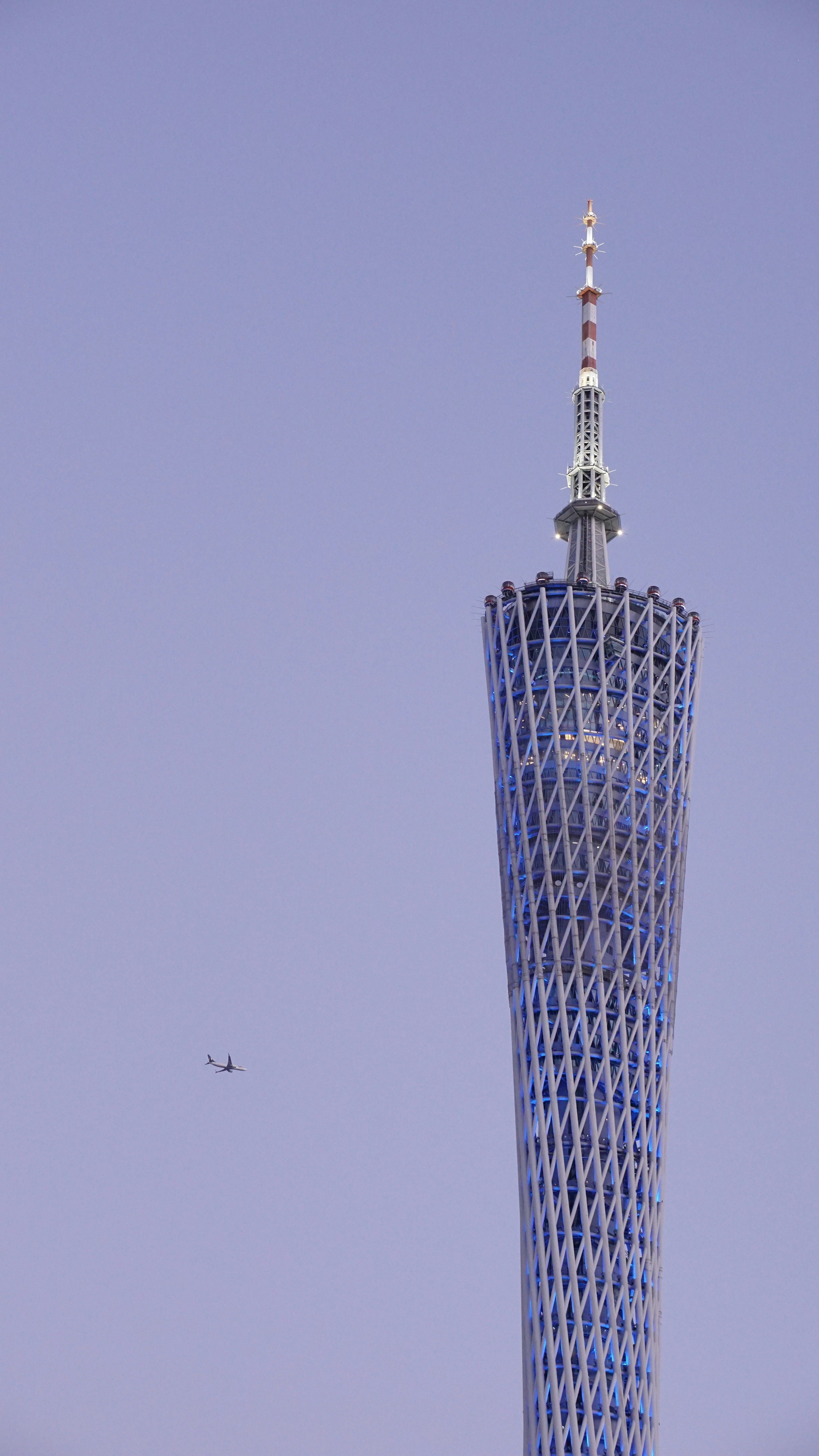 A tall tower with a plane flying nearby.