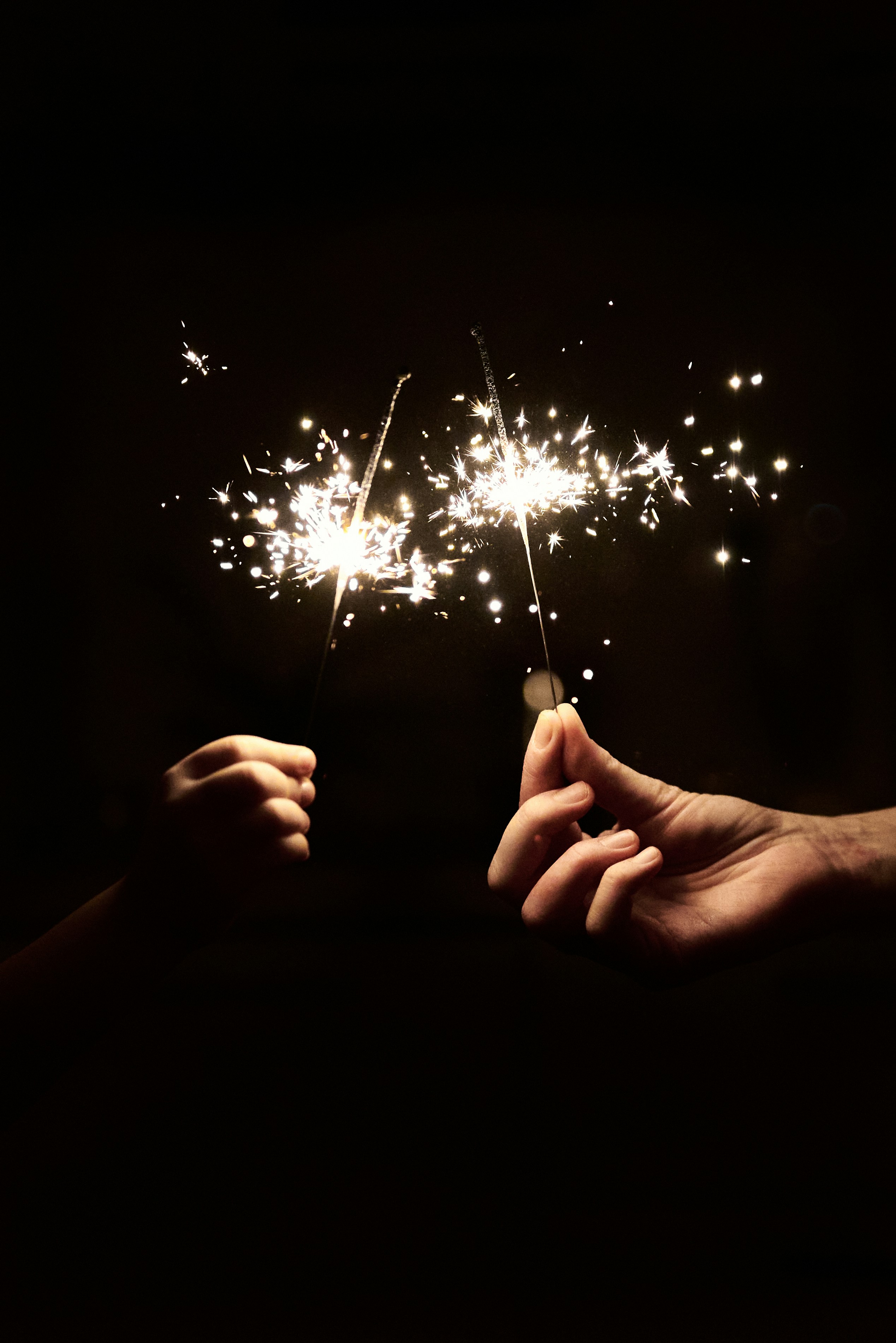 Mãos segurando fogos de artilharia contra um fundo escuro