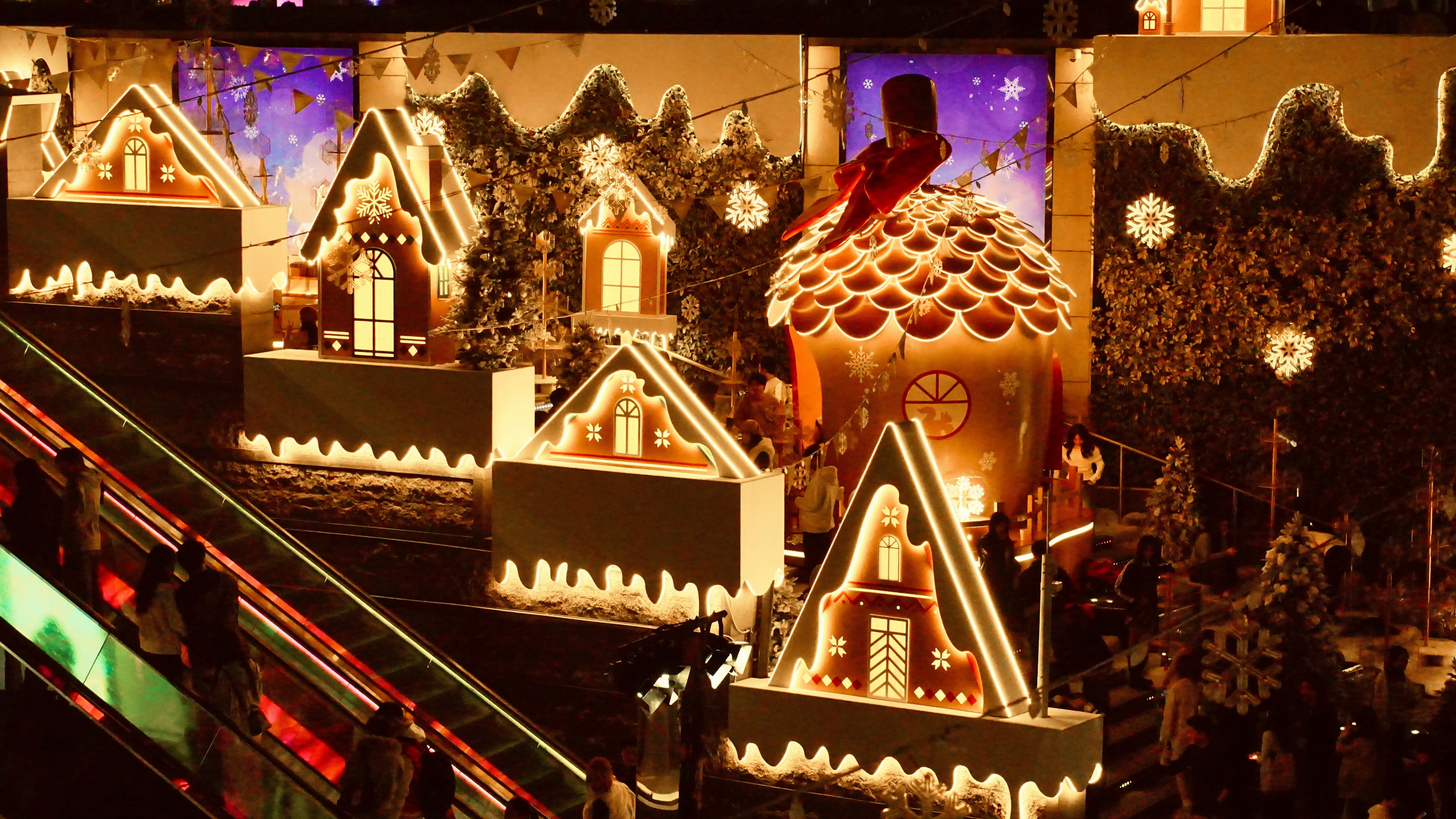 Gingerbread houses and festive lights decorate a winter scene.