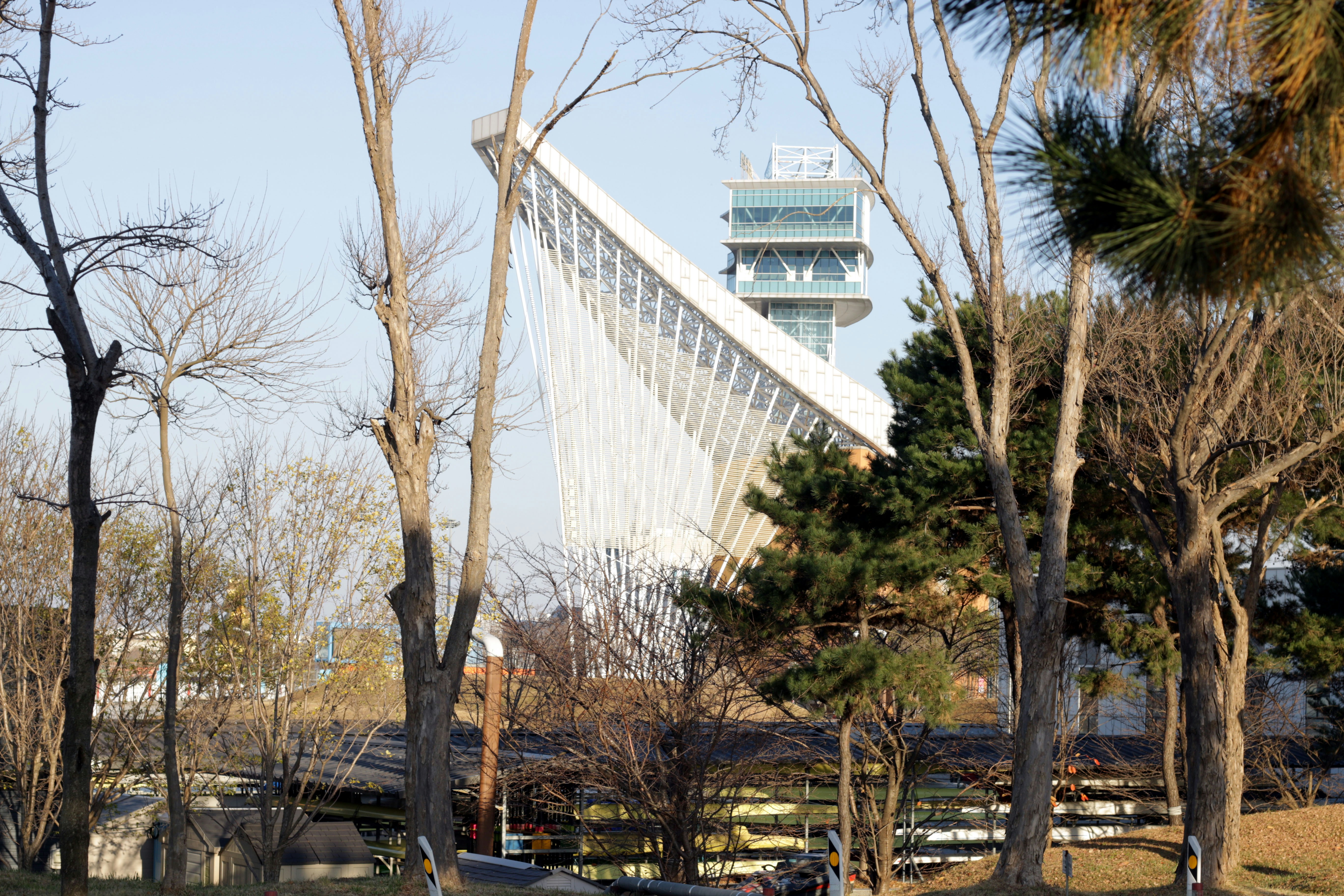 겨울철 기모 후드 원피스 스타일링 - Modern stadium structure with tall tower and trees