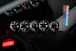 Five car dashboard gauges illuminated at night.