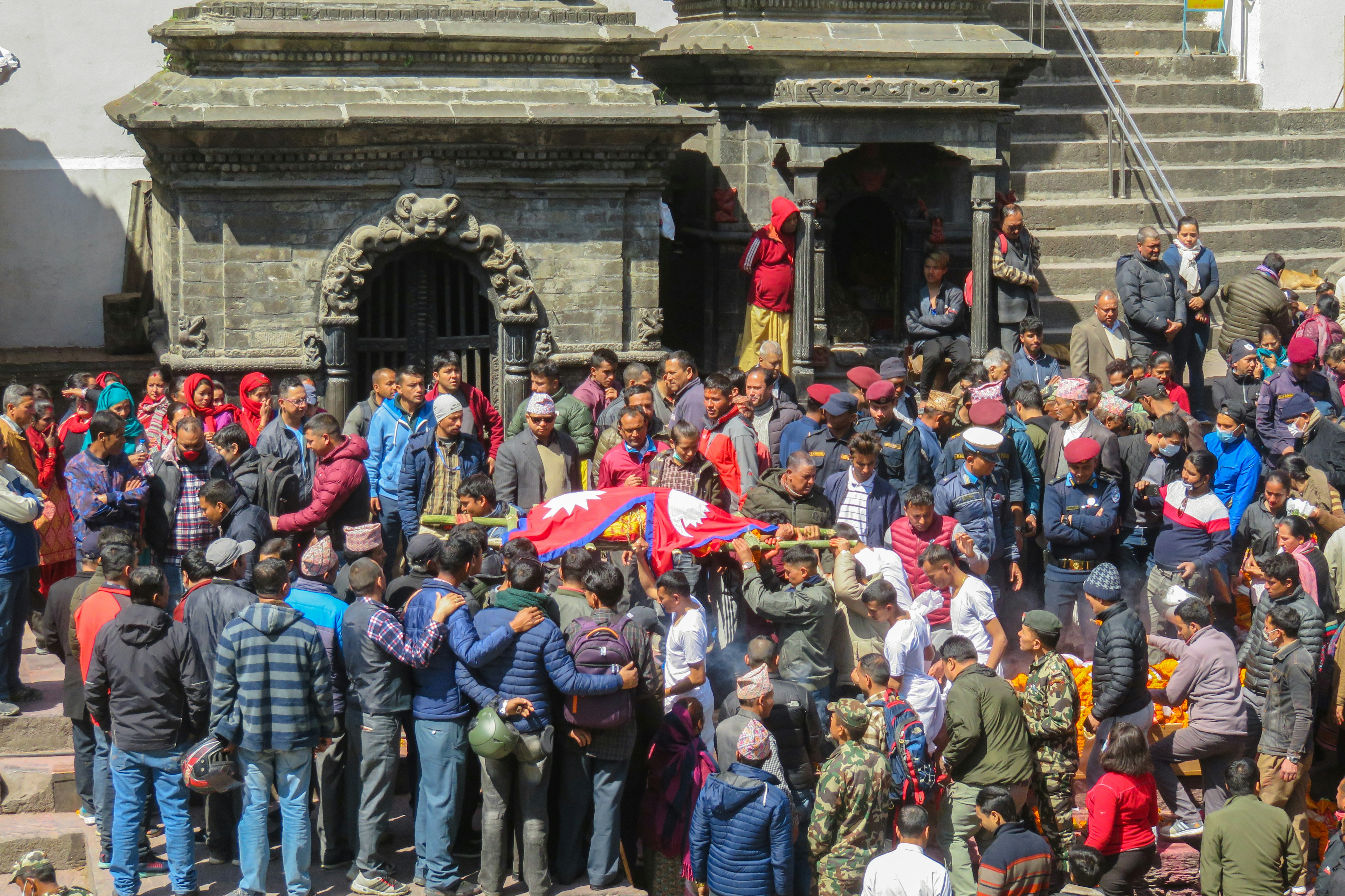 Young people holding placards during a peaceful protest in Kathmandu, with Balendra Shah visible in the background observing or addressing the crowd.