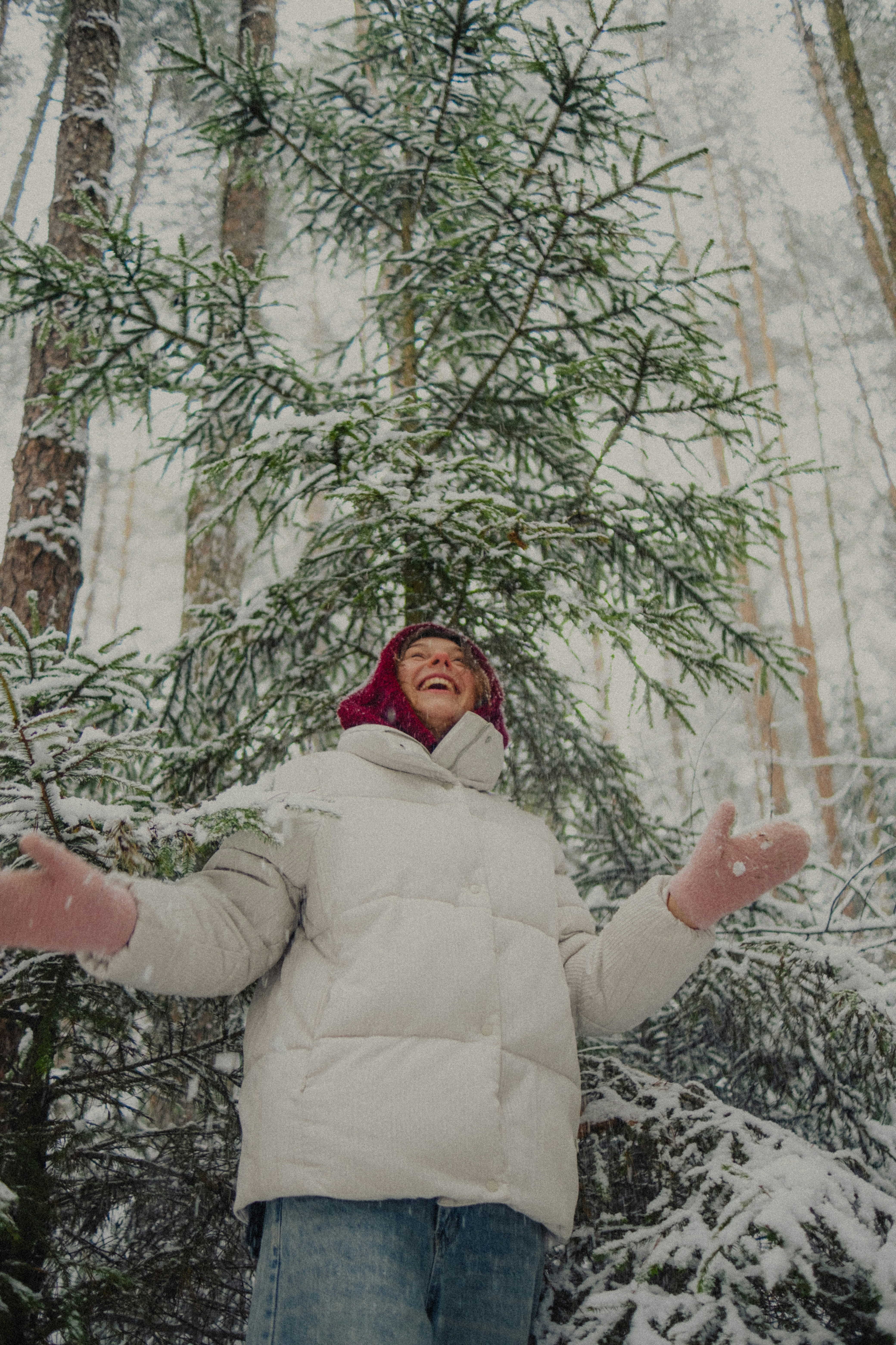 A woman laughing in a snowy forest.