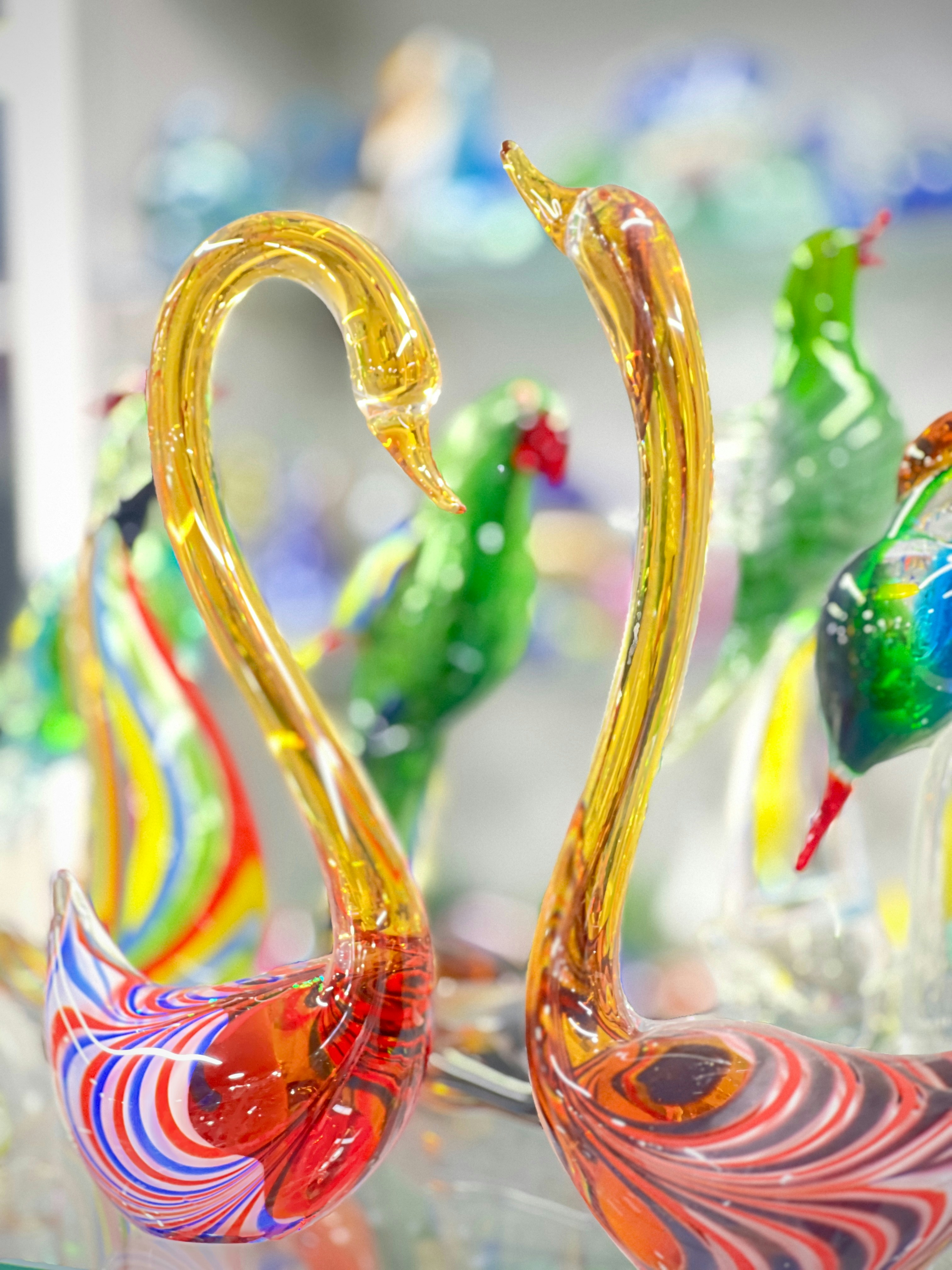 Two glass swans with colorful bases