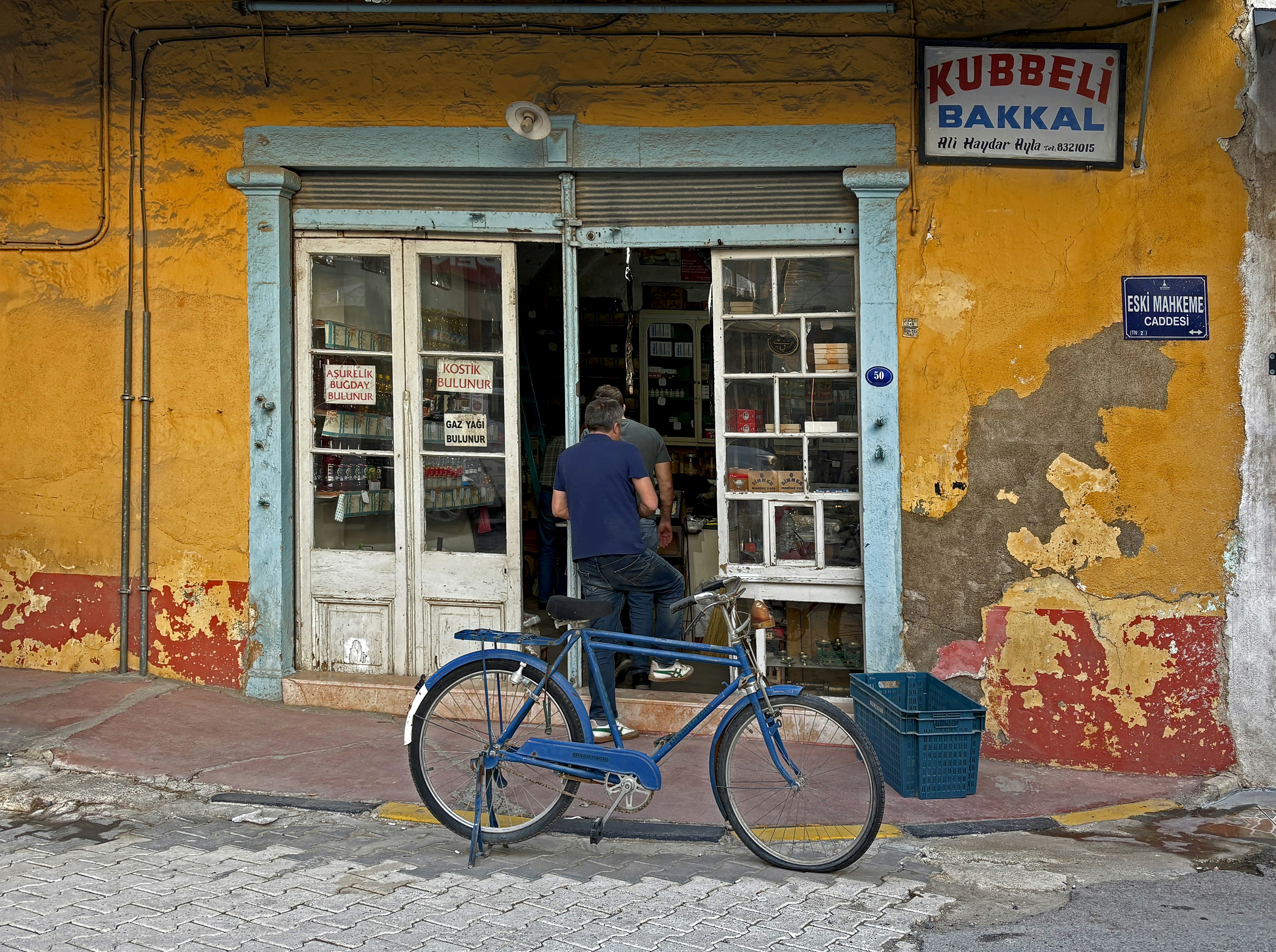 Blue bicycle parked outside a yellow shop