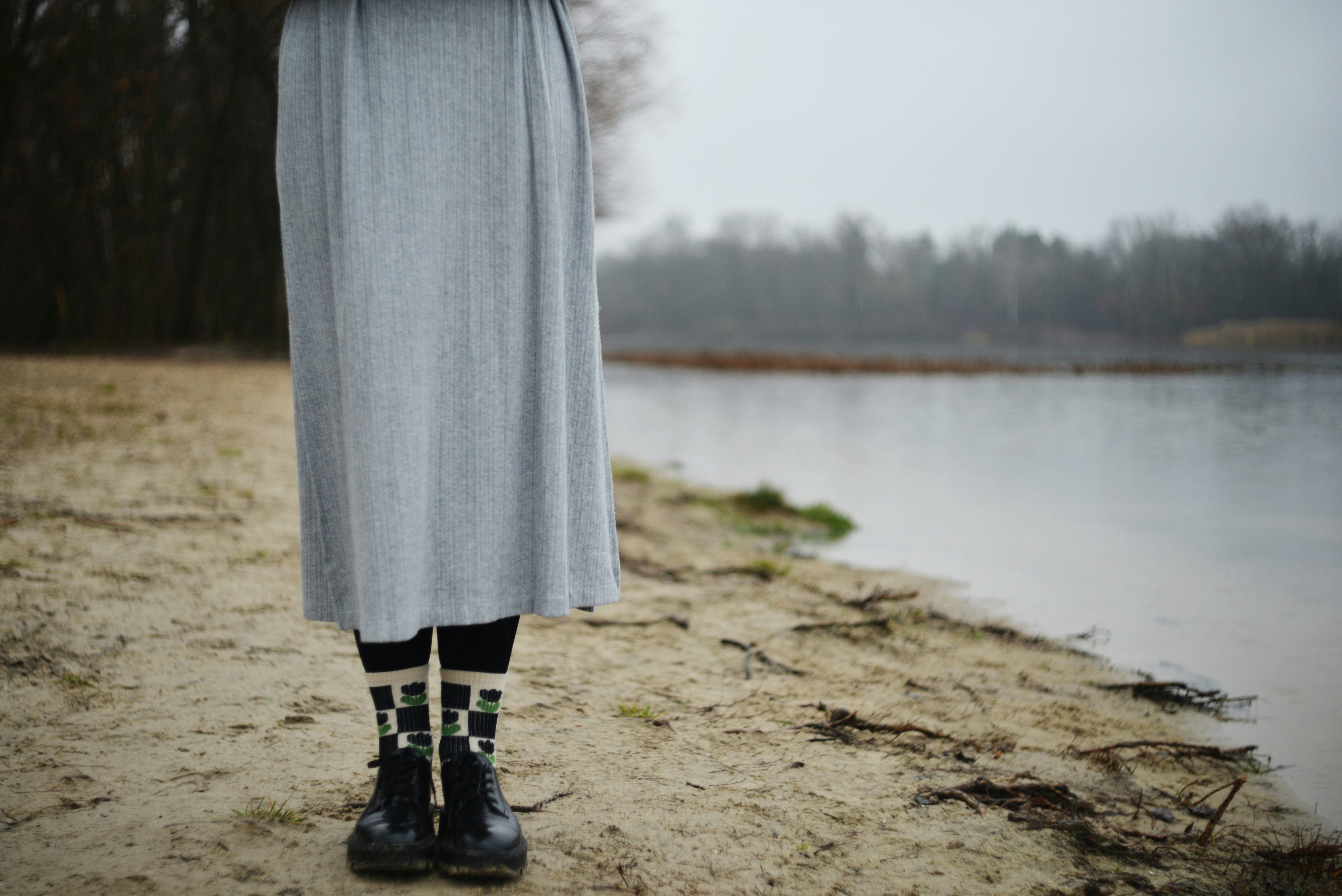 Person in skirt and patterned socks by water