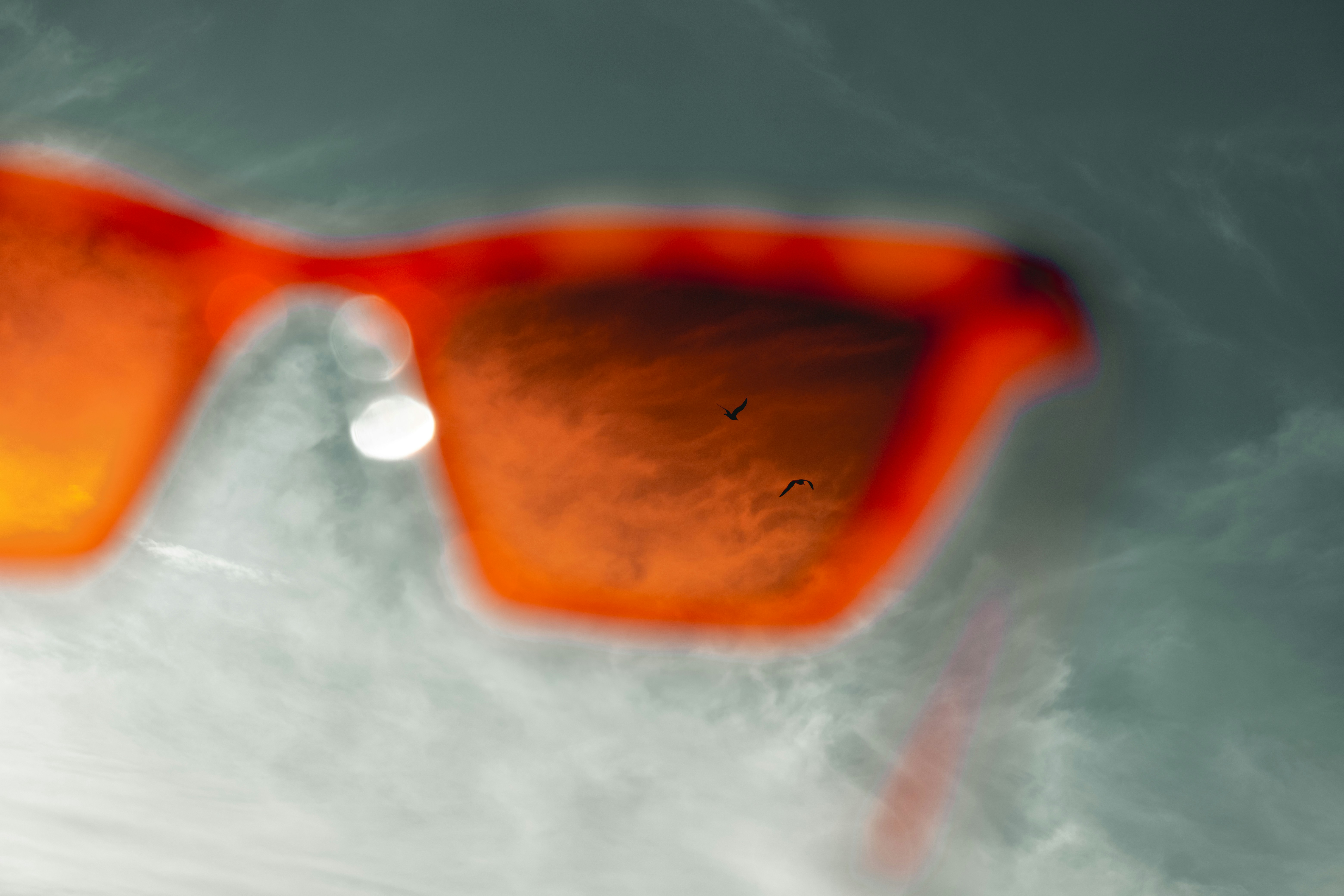 Close-up of orange-tinted sunglasses with reflection