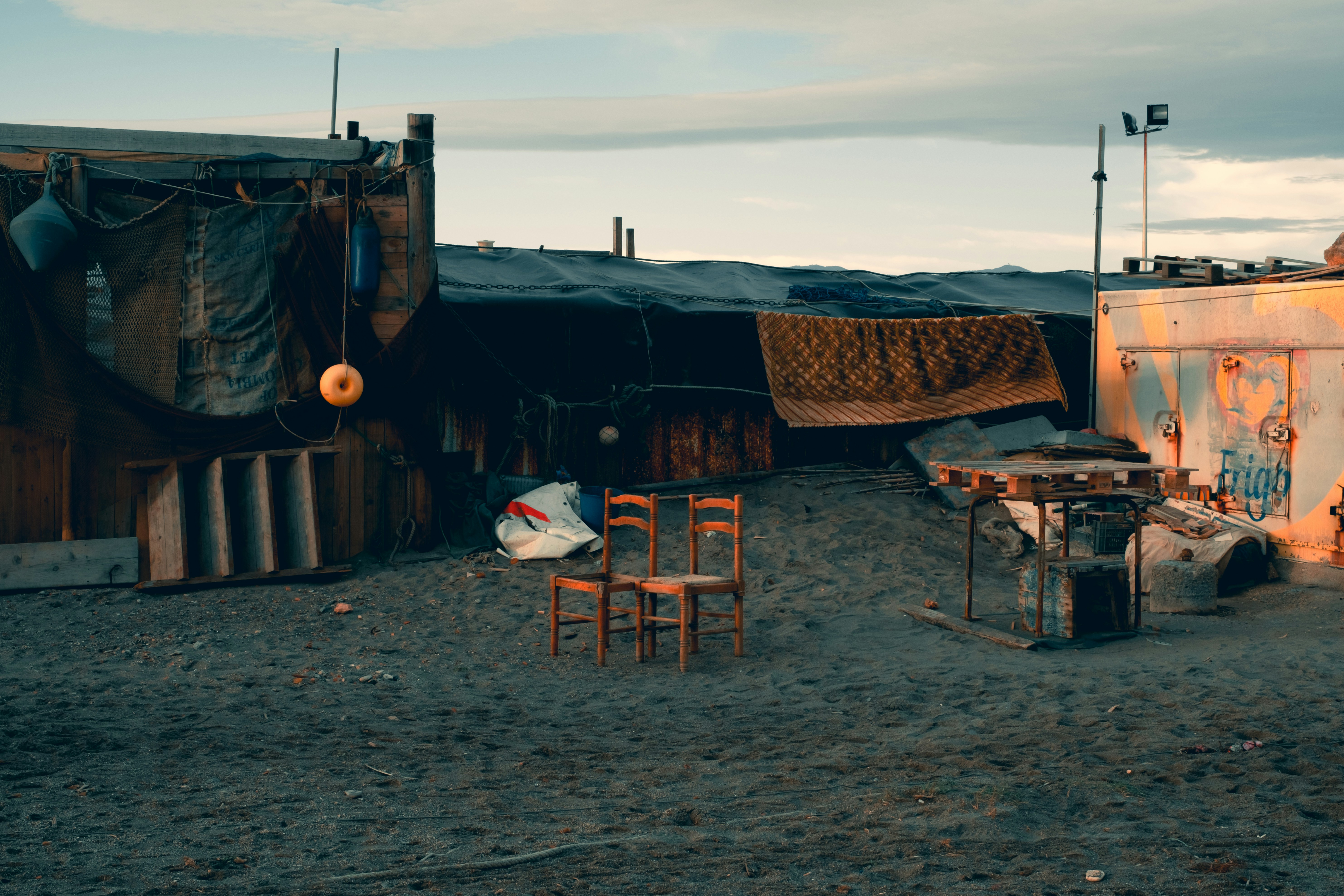 Makeshift shelters and chairs in a desolate area.