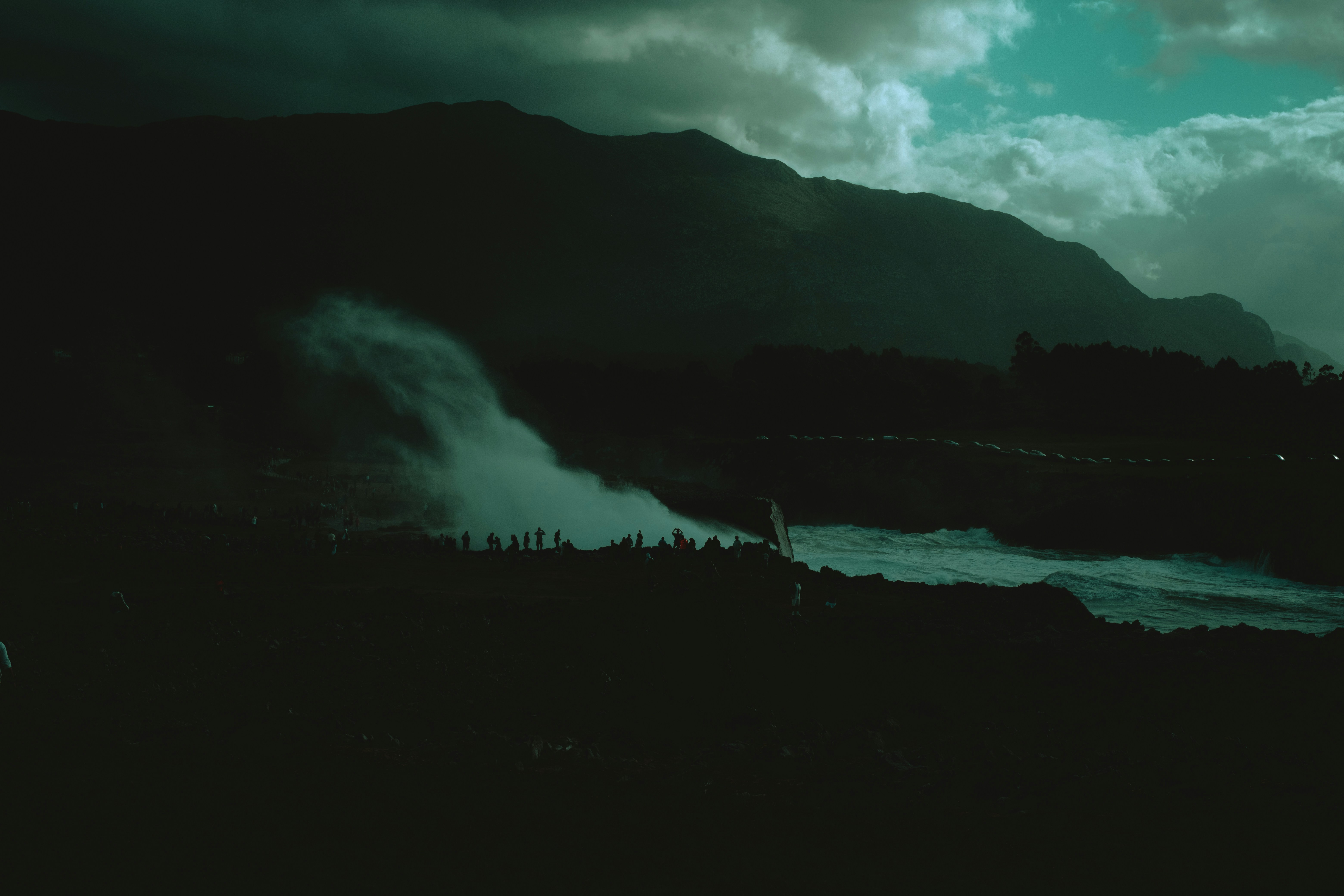 Misty waterfall cascades down a dark mountain slope