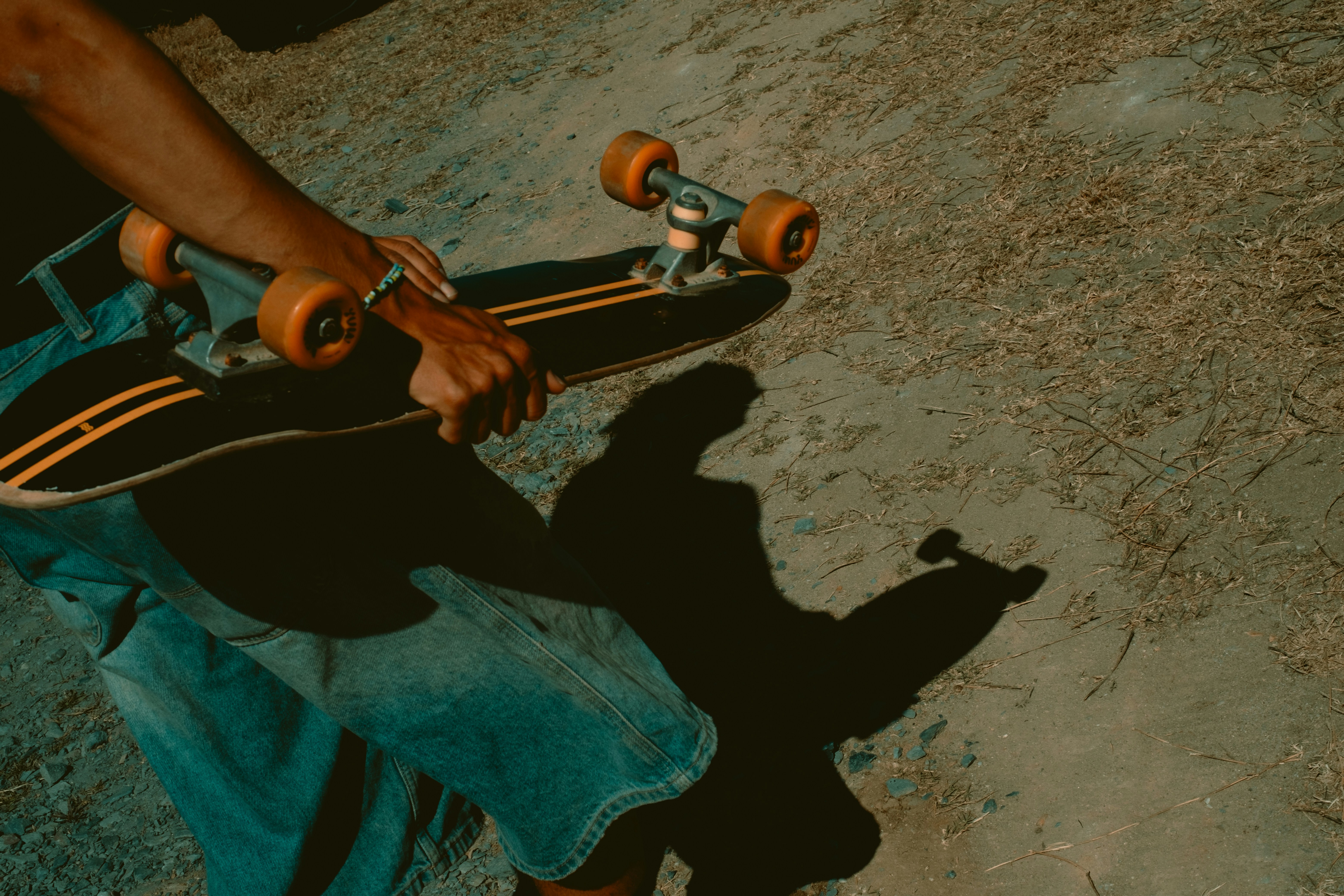 Person holding a skateboard with orange wheels
