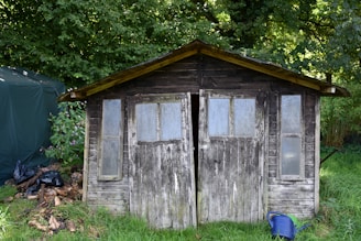 A weathered wooden shed with glass windows
