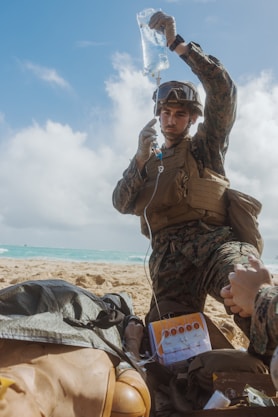 Medic administers iv fluid to casualty on beach
