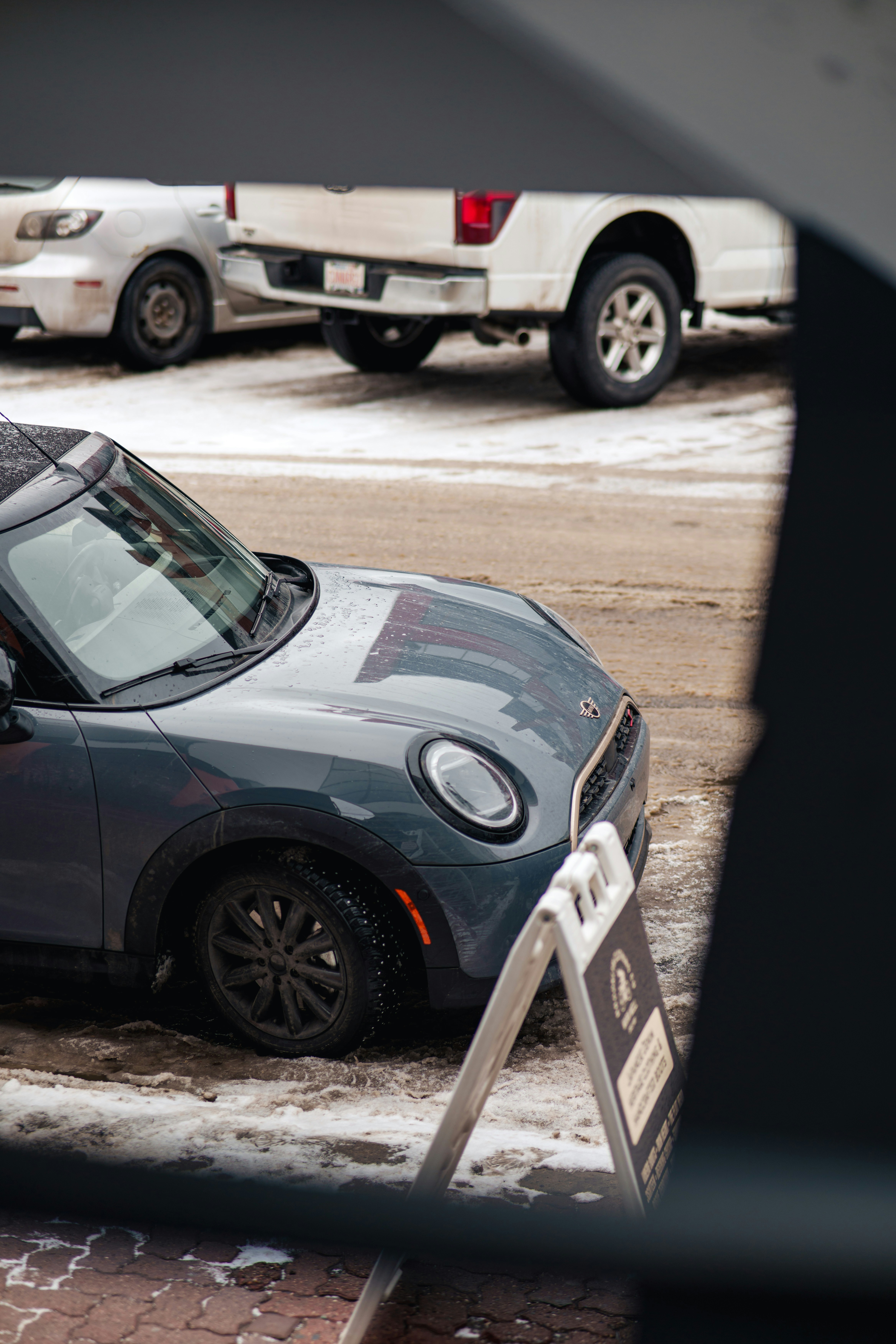 Gray mini cooper parked on snowy street.