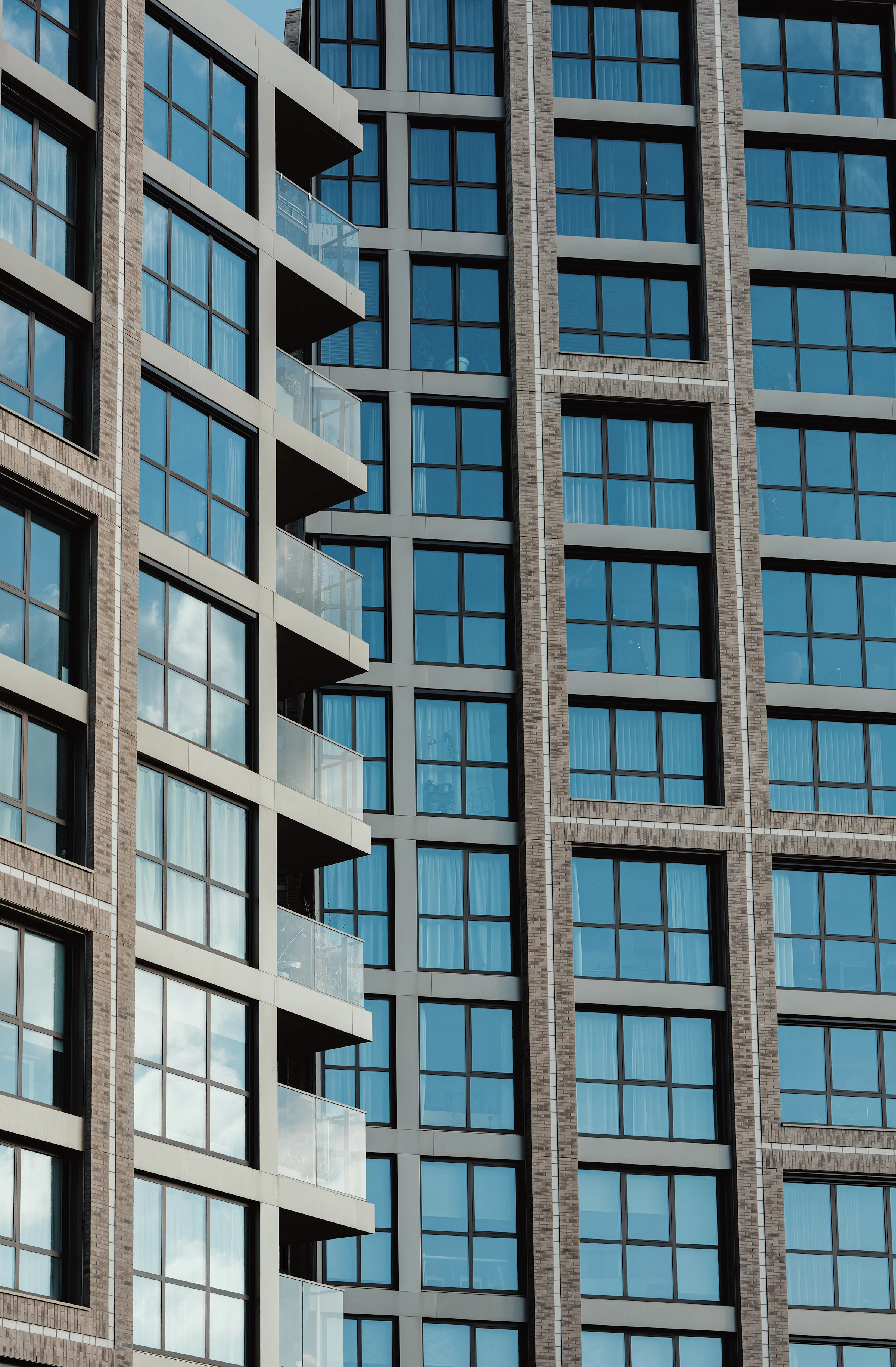 Moderne nieuwbouwgevel met baksteen, antraciet kozijnen en glazen balkons