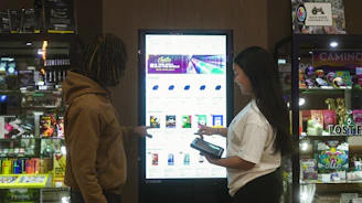 Two people interact with a digital display screen.