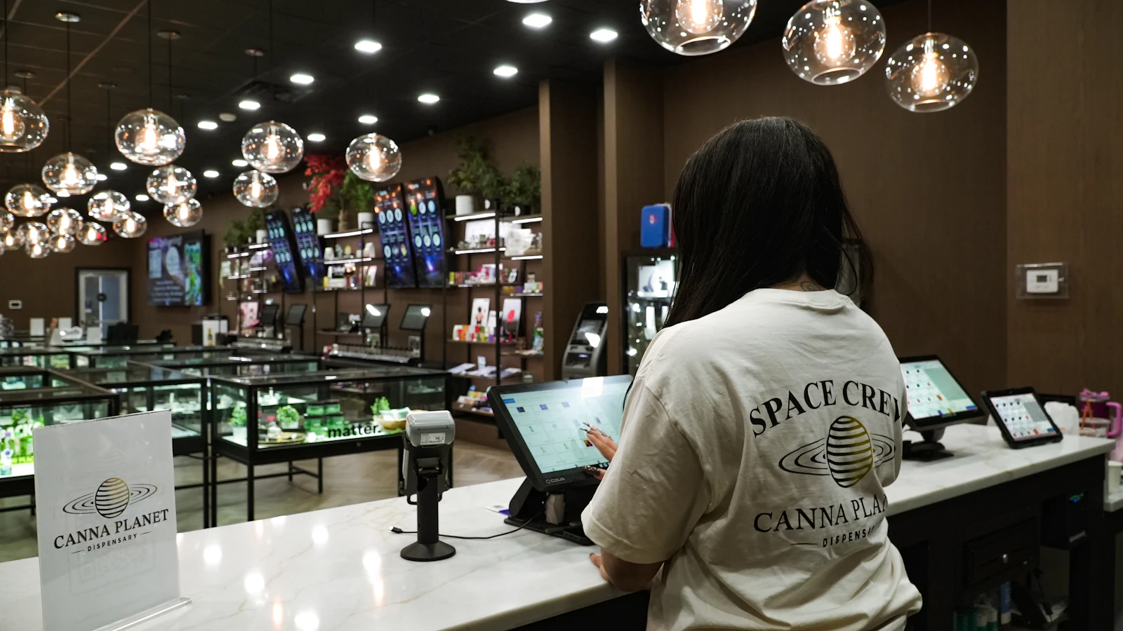Dispensary staff processing a payment at an integrated point-of-sale counter in a USA cannabis store