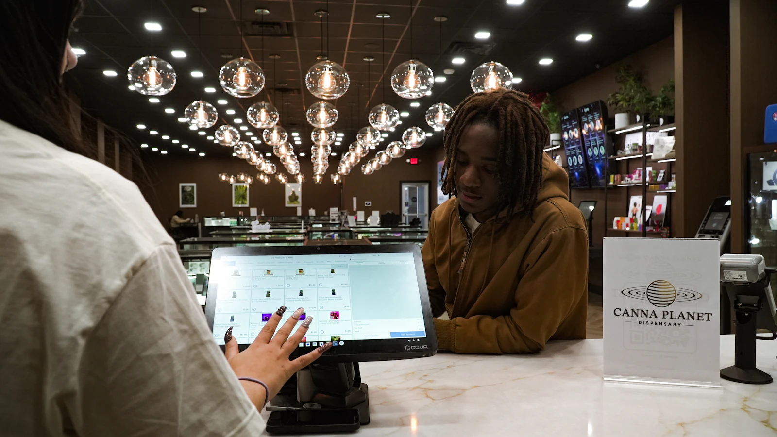 Budtender and customer completing a compliant transaction at a modern dispensary counter