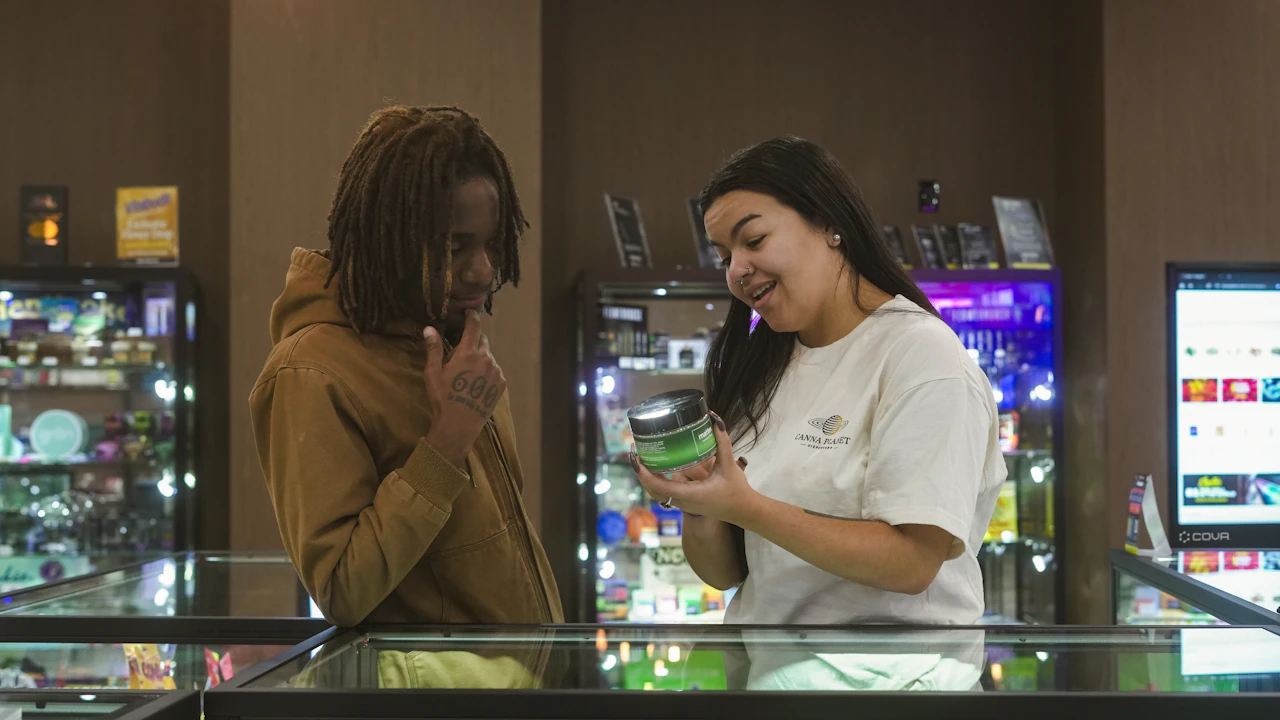Budtender showing a cannabis product to a customer at a dispensary counter while building a customer relationship