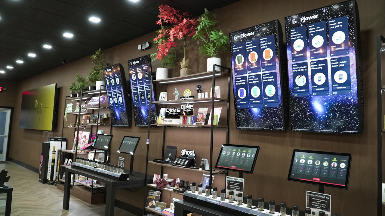 Modern dispensary retail display with digital menu screens above the product cases