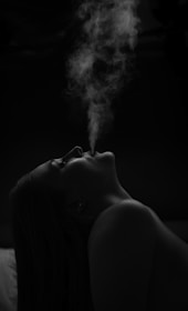 Woman exhaling smoke against a dark background