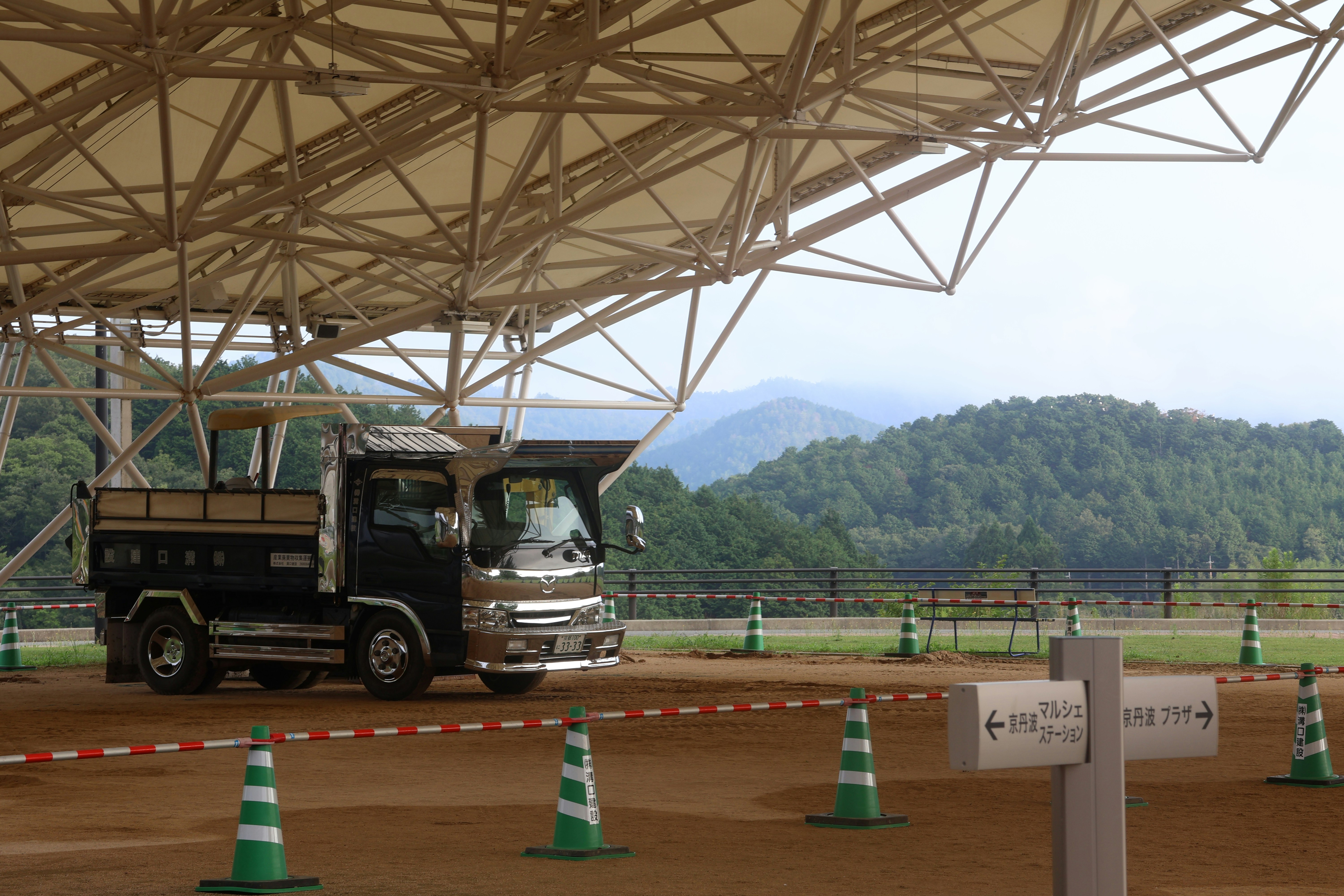 A dark truck parked under a large canopy.