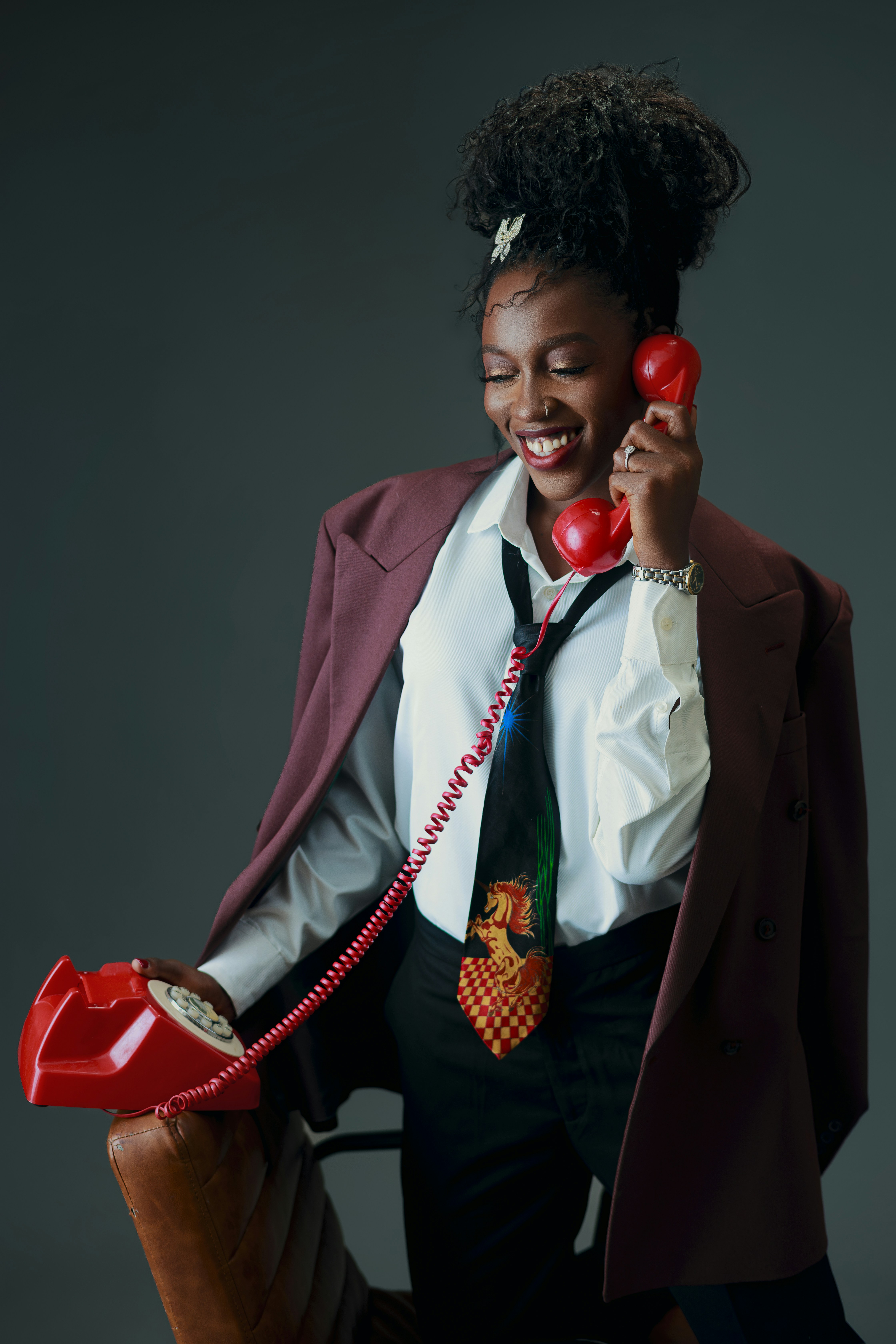 Frau im stylischen Anzug hält ein Vintage-Rottelefon