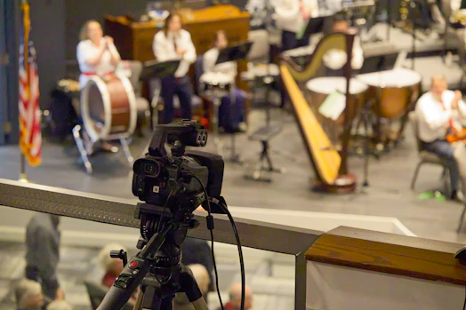 A camera records a live orchestra performance on stage.