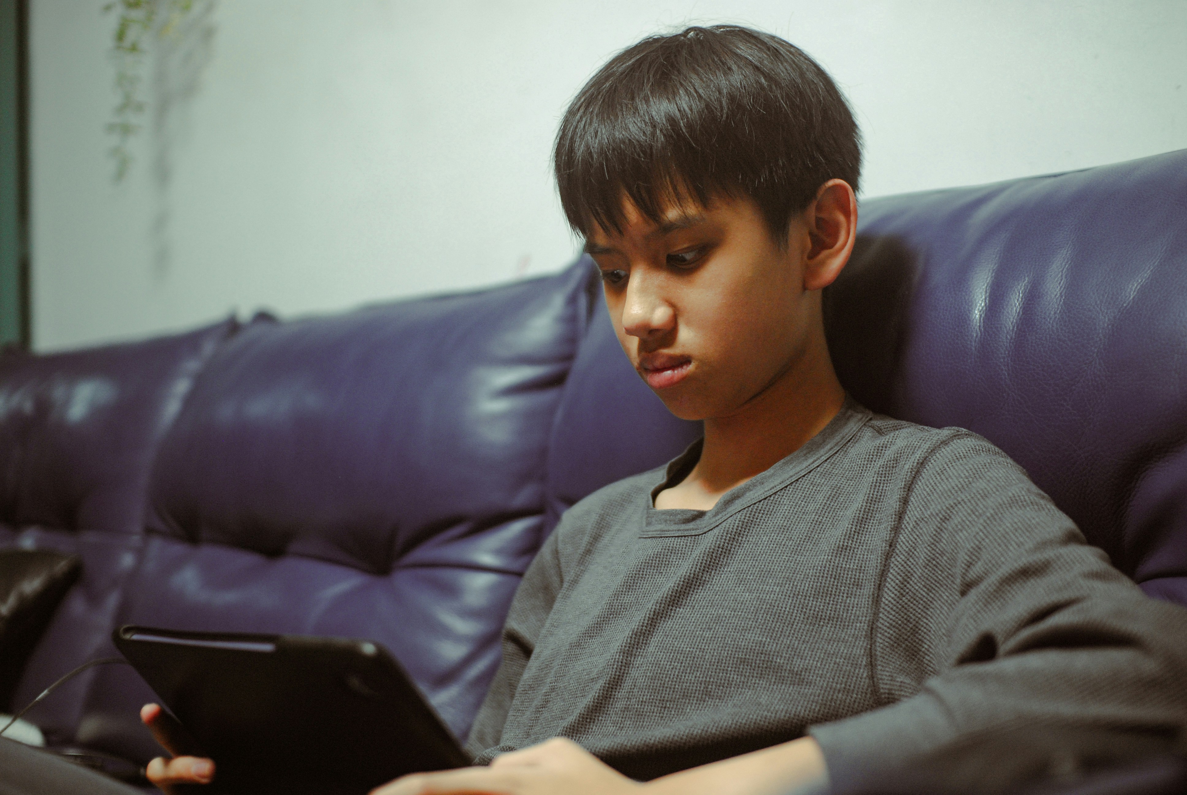 Young boy looking at a tablet on a couch