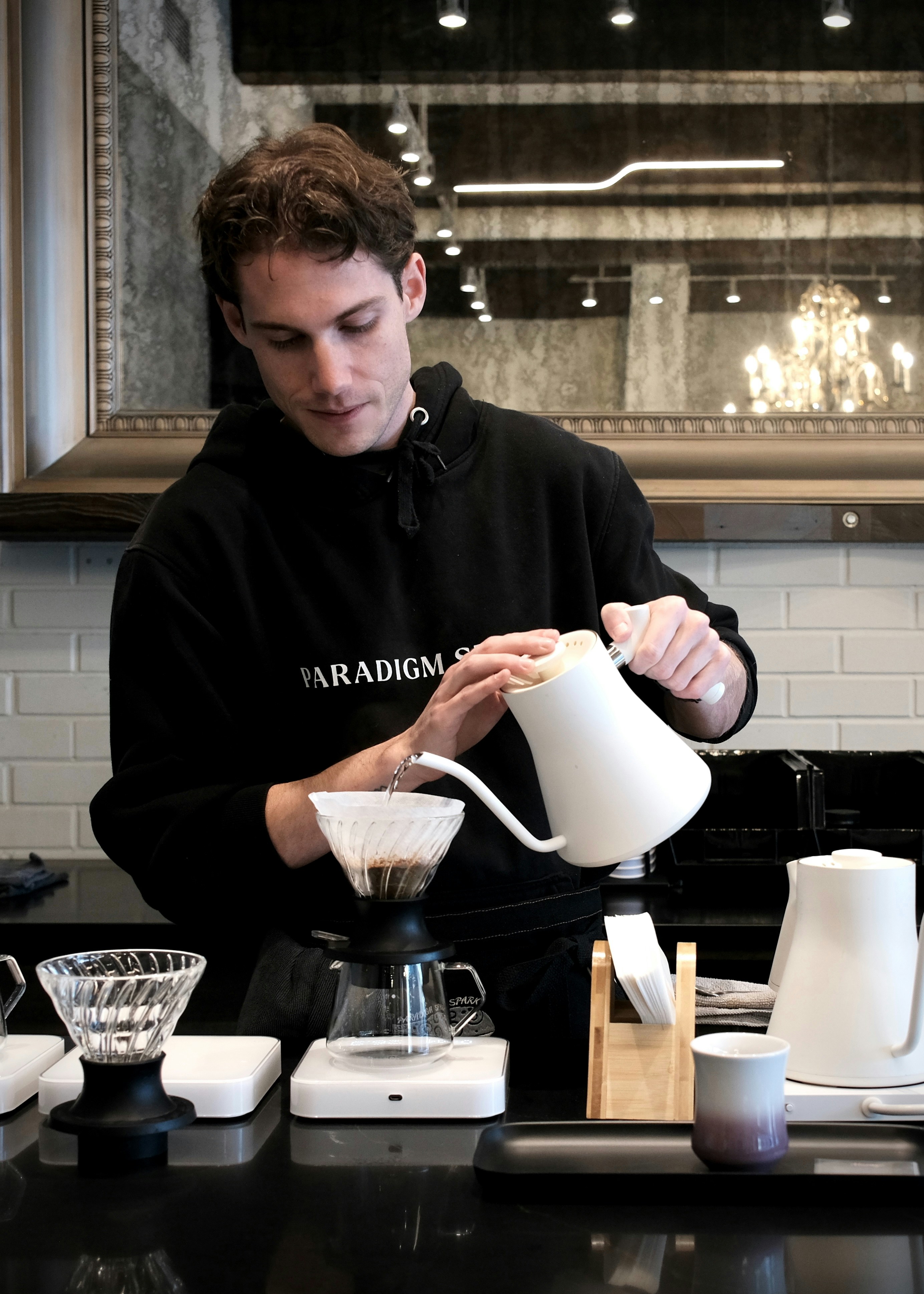 Barista carefully pouring hot water into coffee dripper.