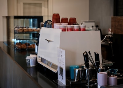 Espresso machine with cups and pastries in background.