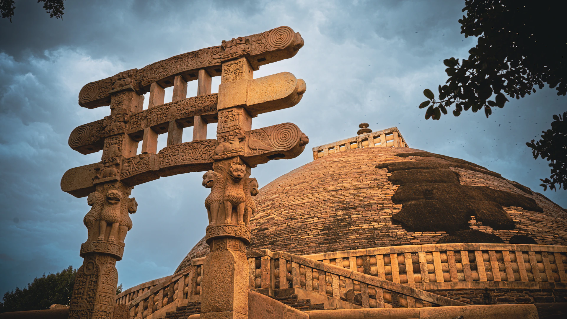 Ancient stone gateway and stupa against cloudy sky