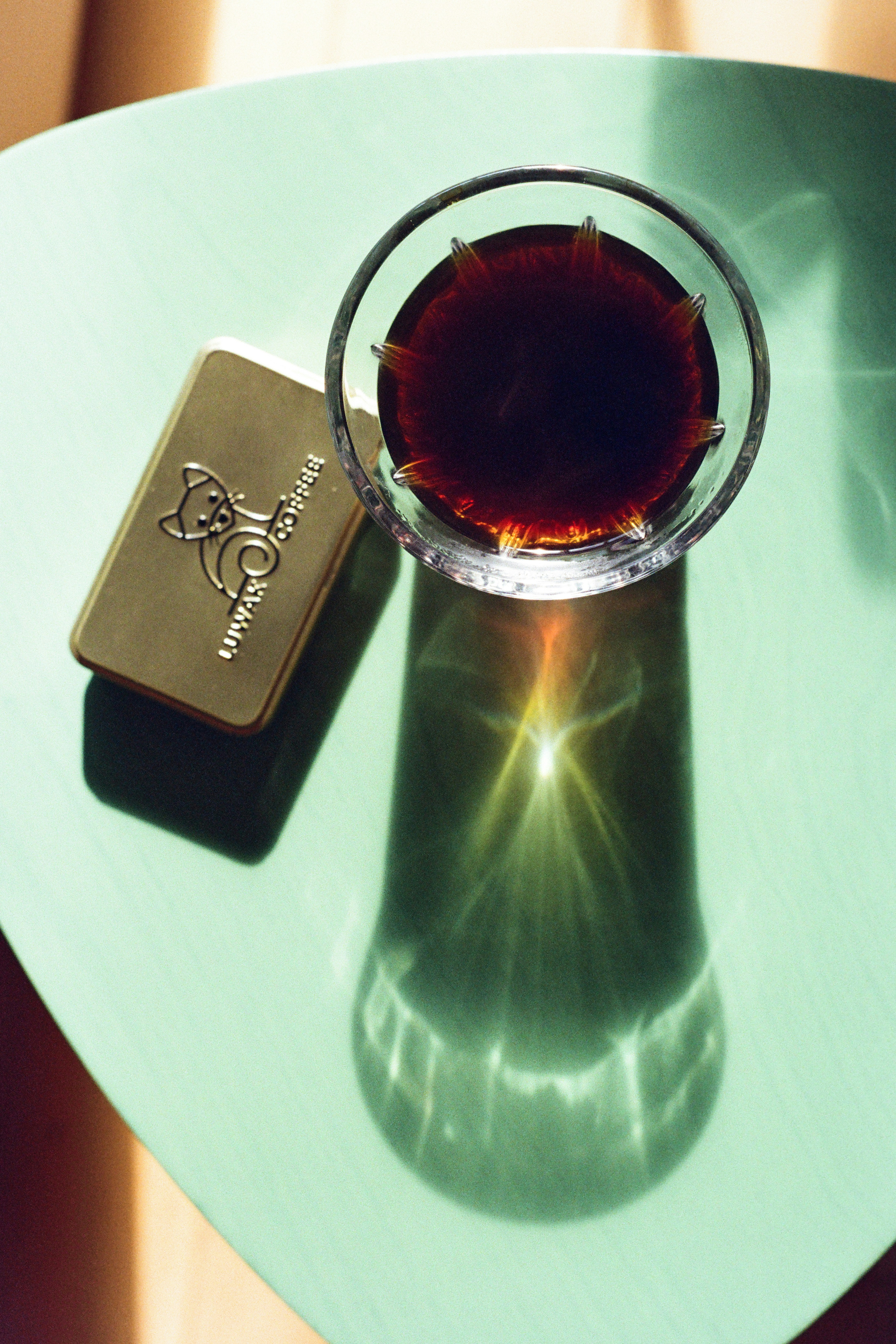 A glass of dark liquid casts a shadow.