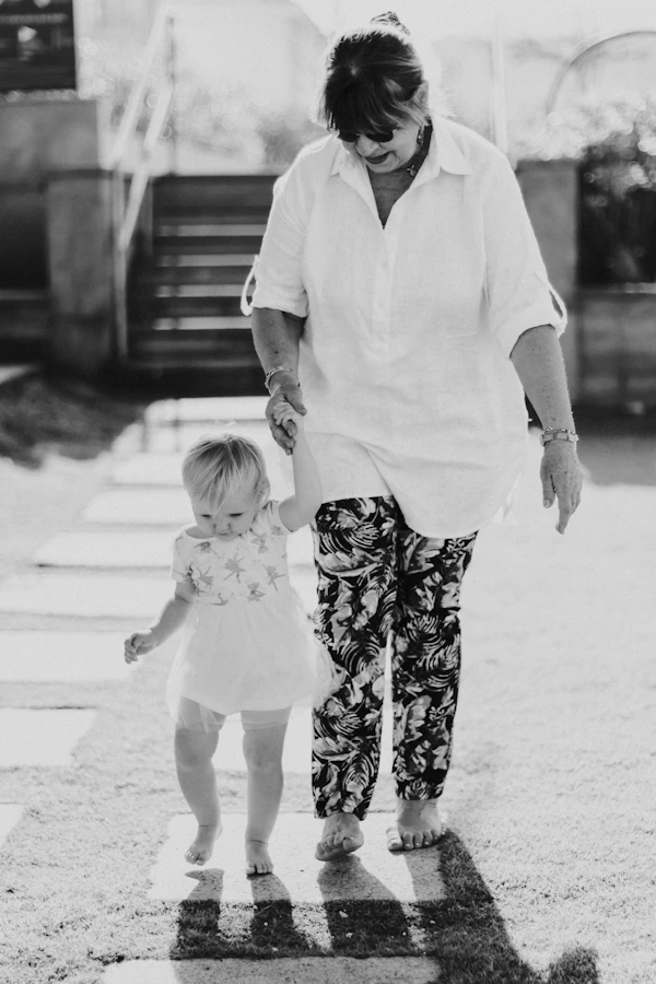 Woman holding toddler's hand walking on path