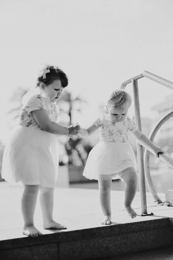 Two young girls holding hands walking down steps