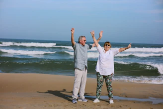Elderly couple celebrating on a sandy beach.