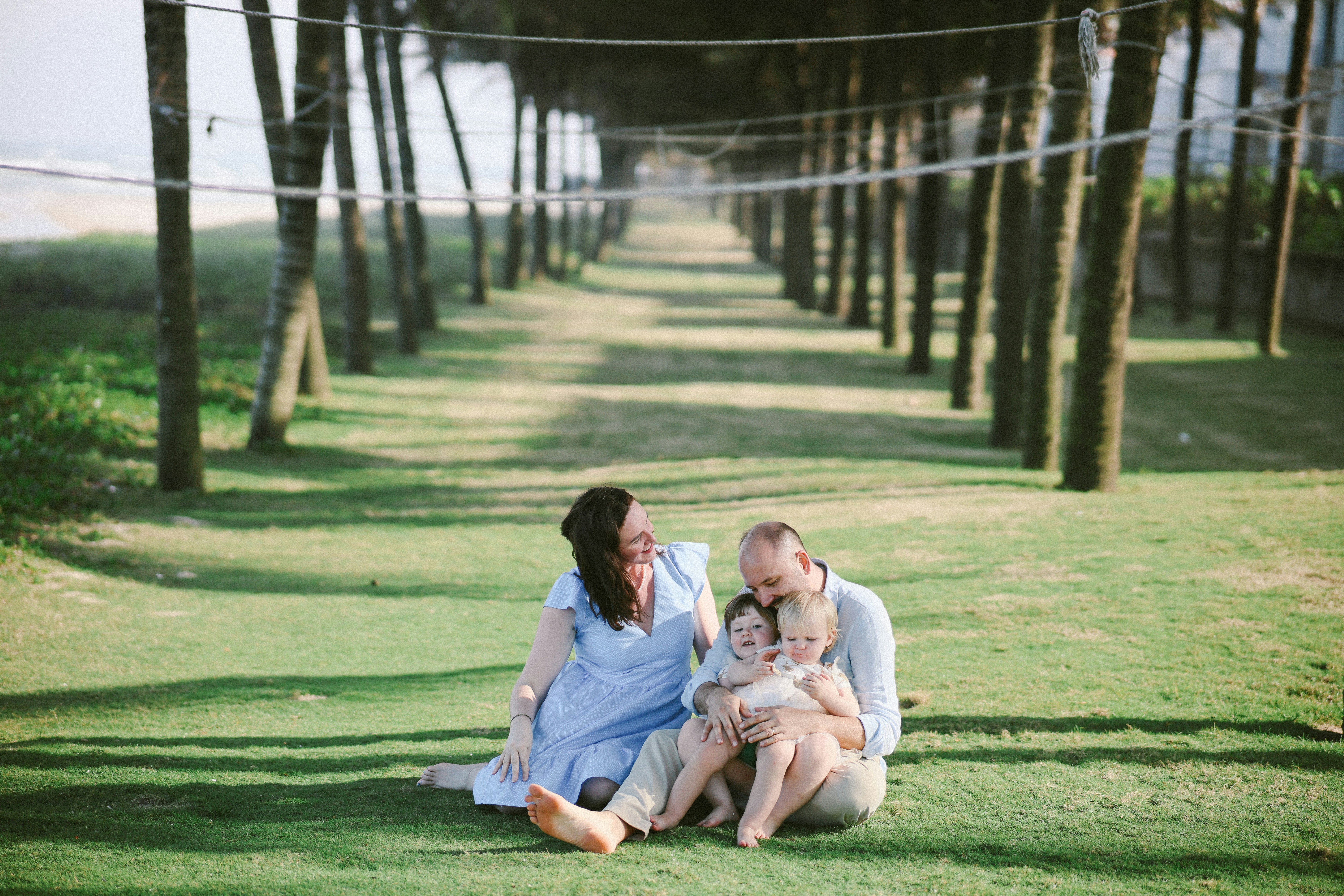 Family sitting on grass under trees