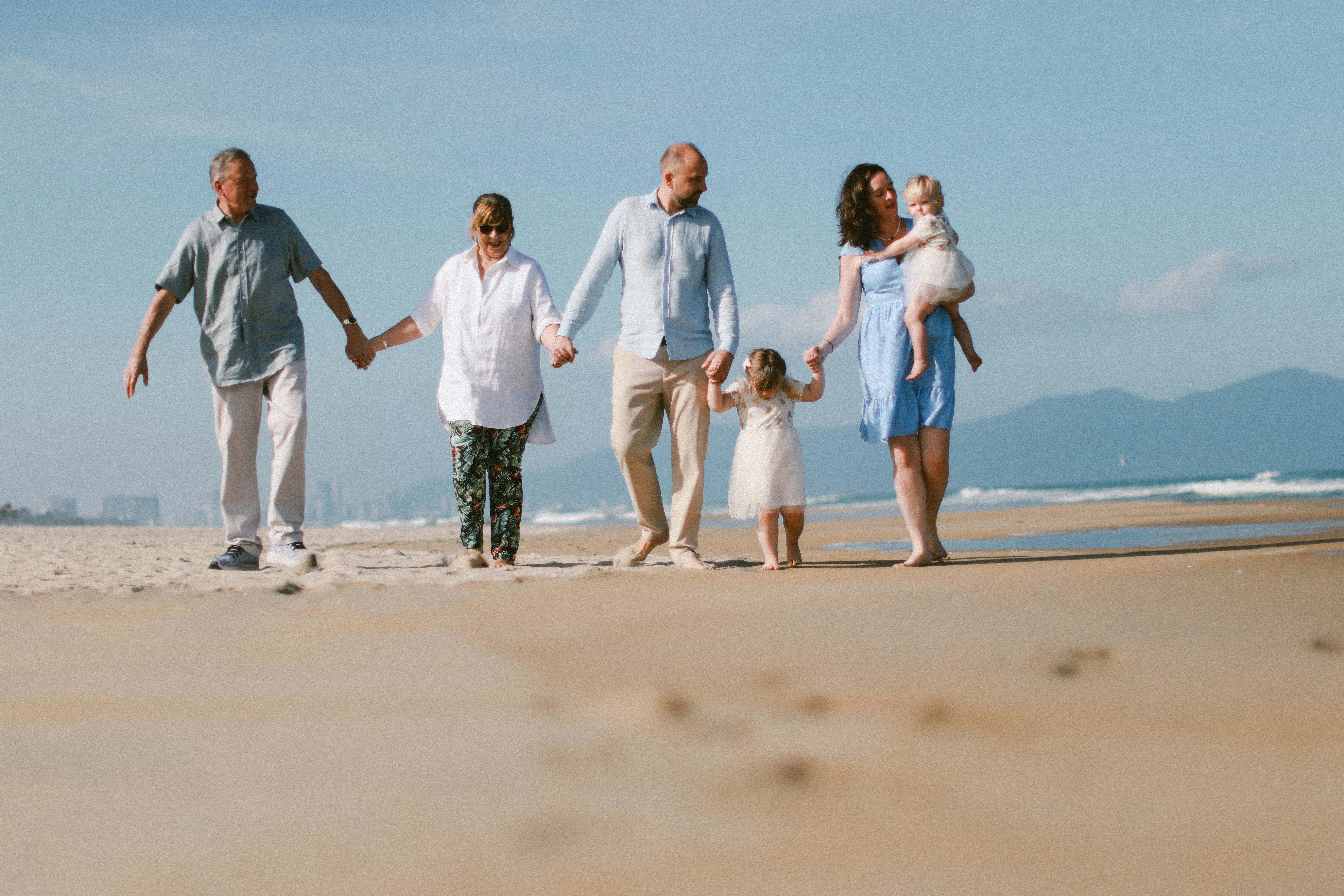 Una famiglia multigenerazionale cammina su una spiaggia sabbiosa.