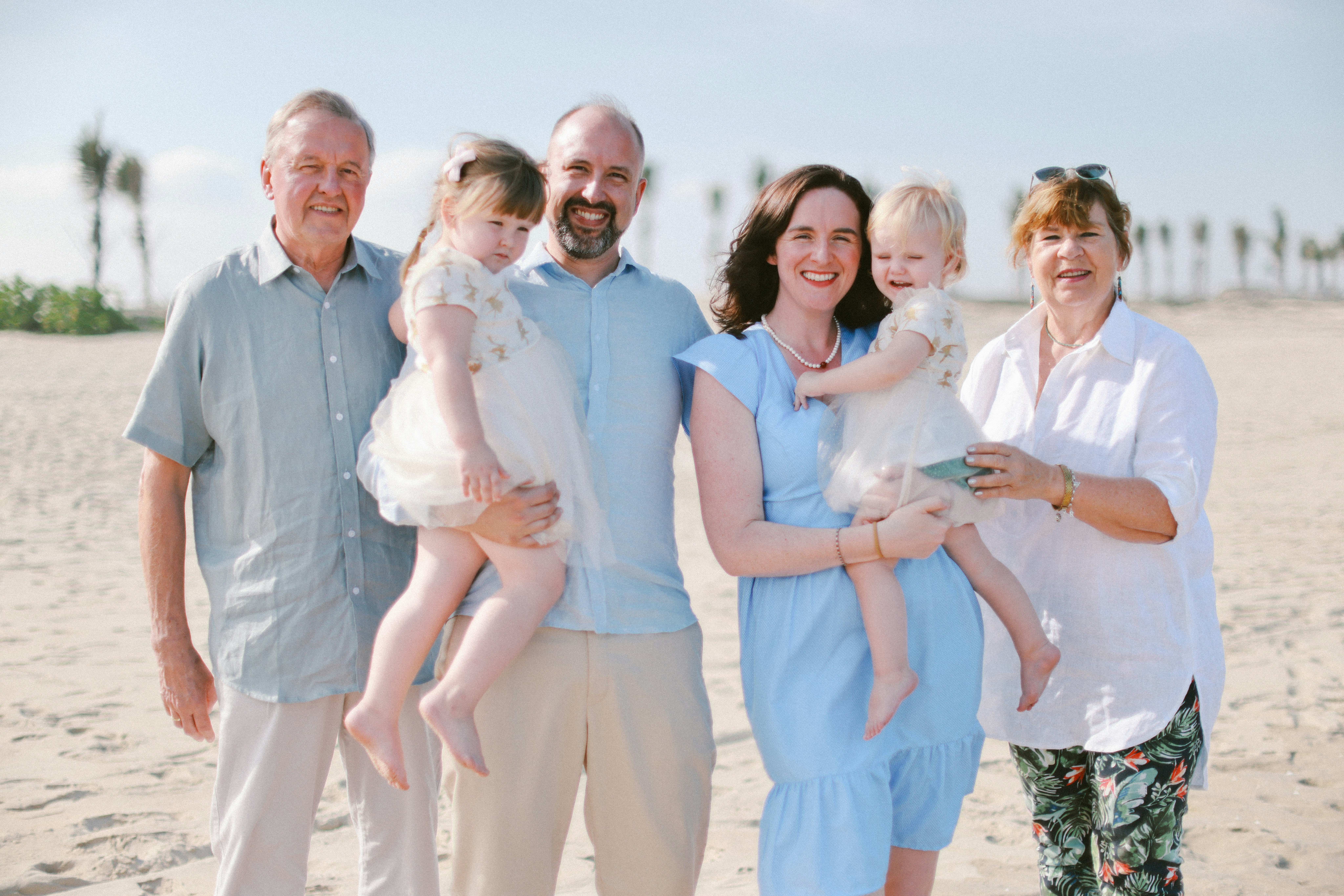 A multi-generational family posing on a sandy beach