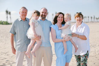A multi-generational family posing on a sandy beach