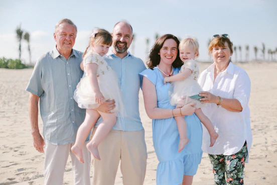 A multi-generational family posing on a sandy beach