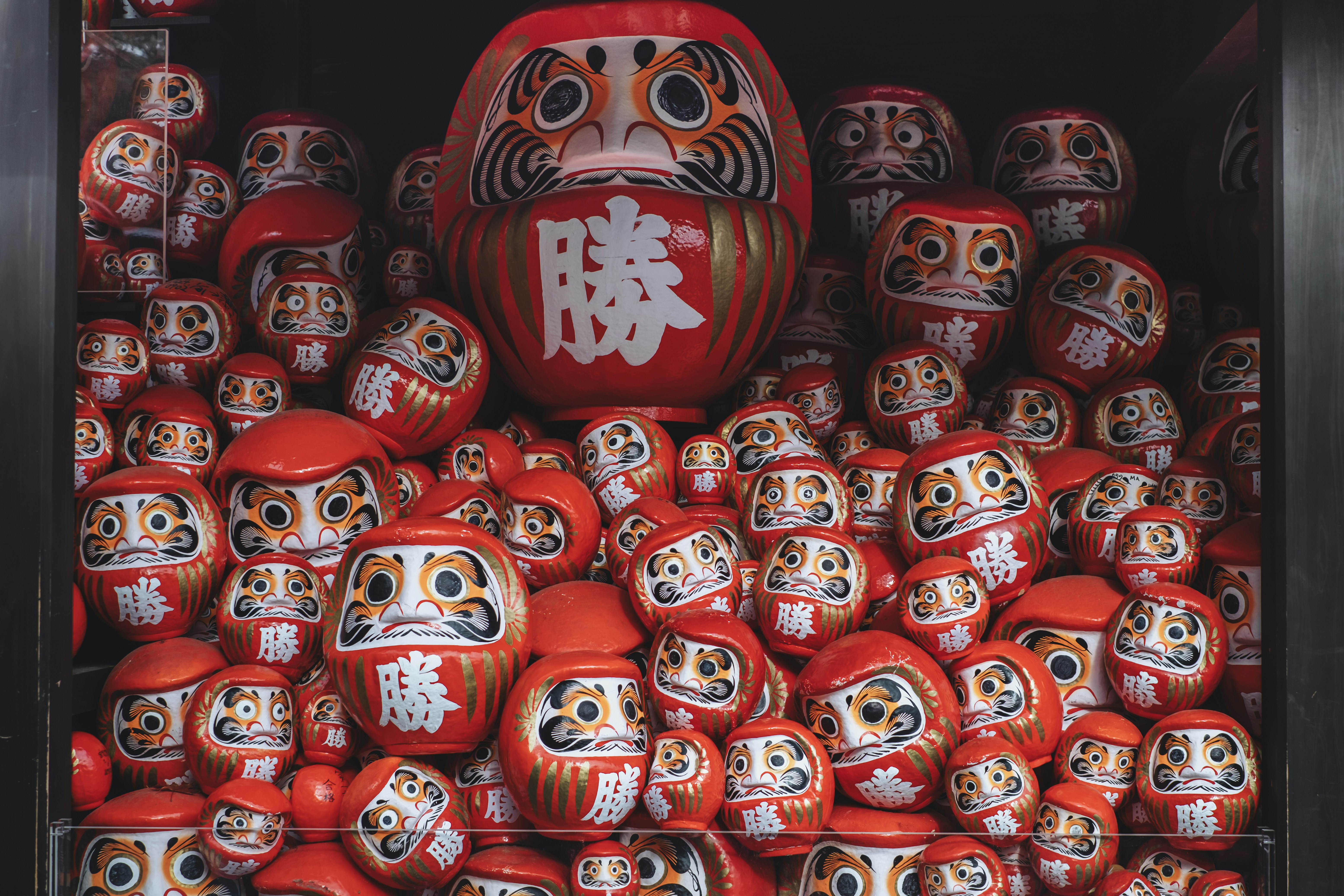 A collection of red daruma dolls with varied sizes.