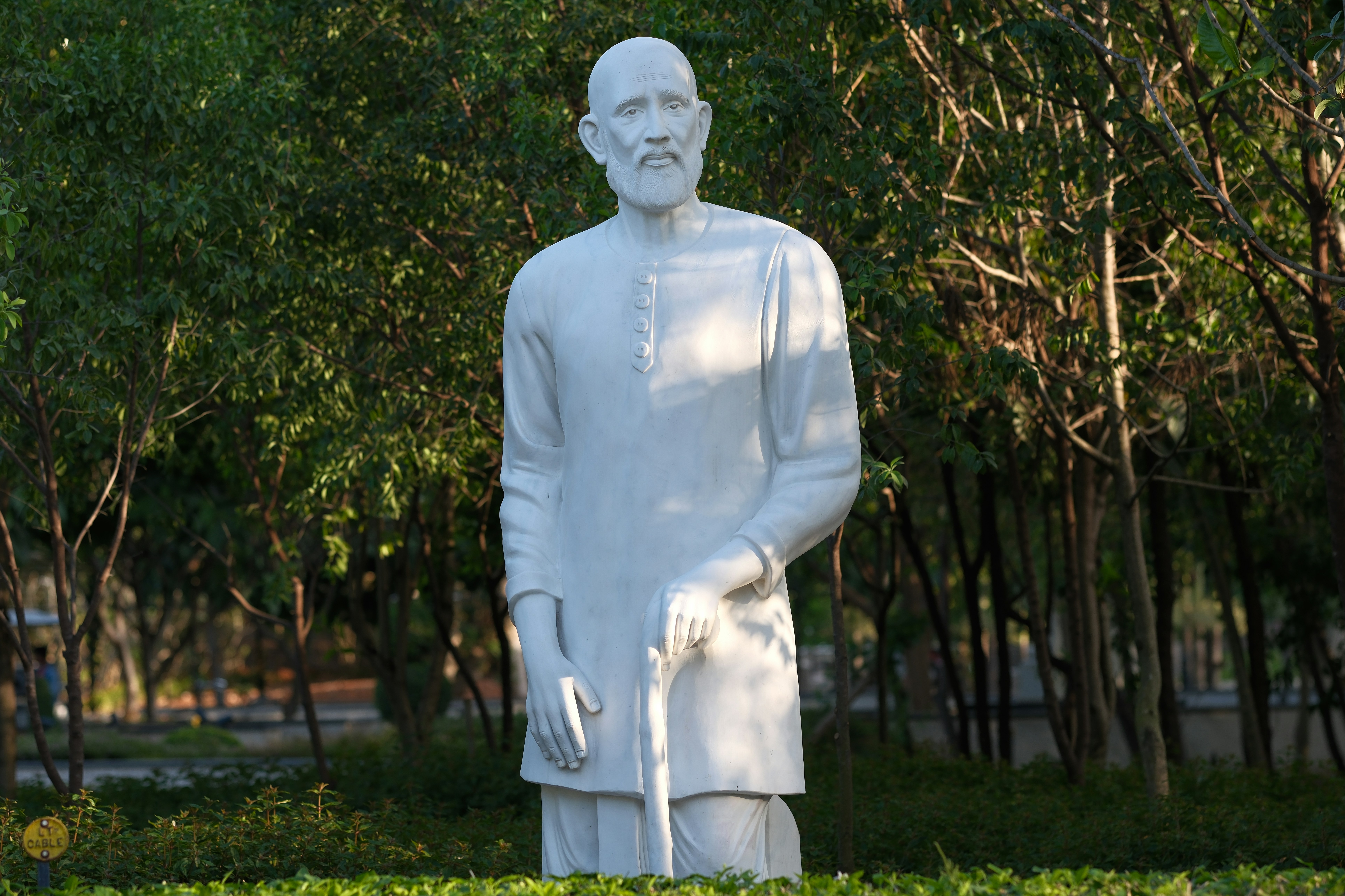 A white marble statue of a man with a cane.