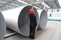 Worker inspects large metal pipes in factory