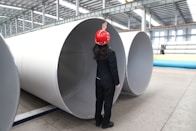 Worker inspects large metal pipes in factory
